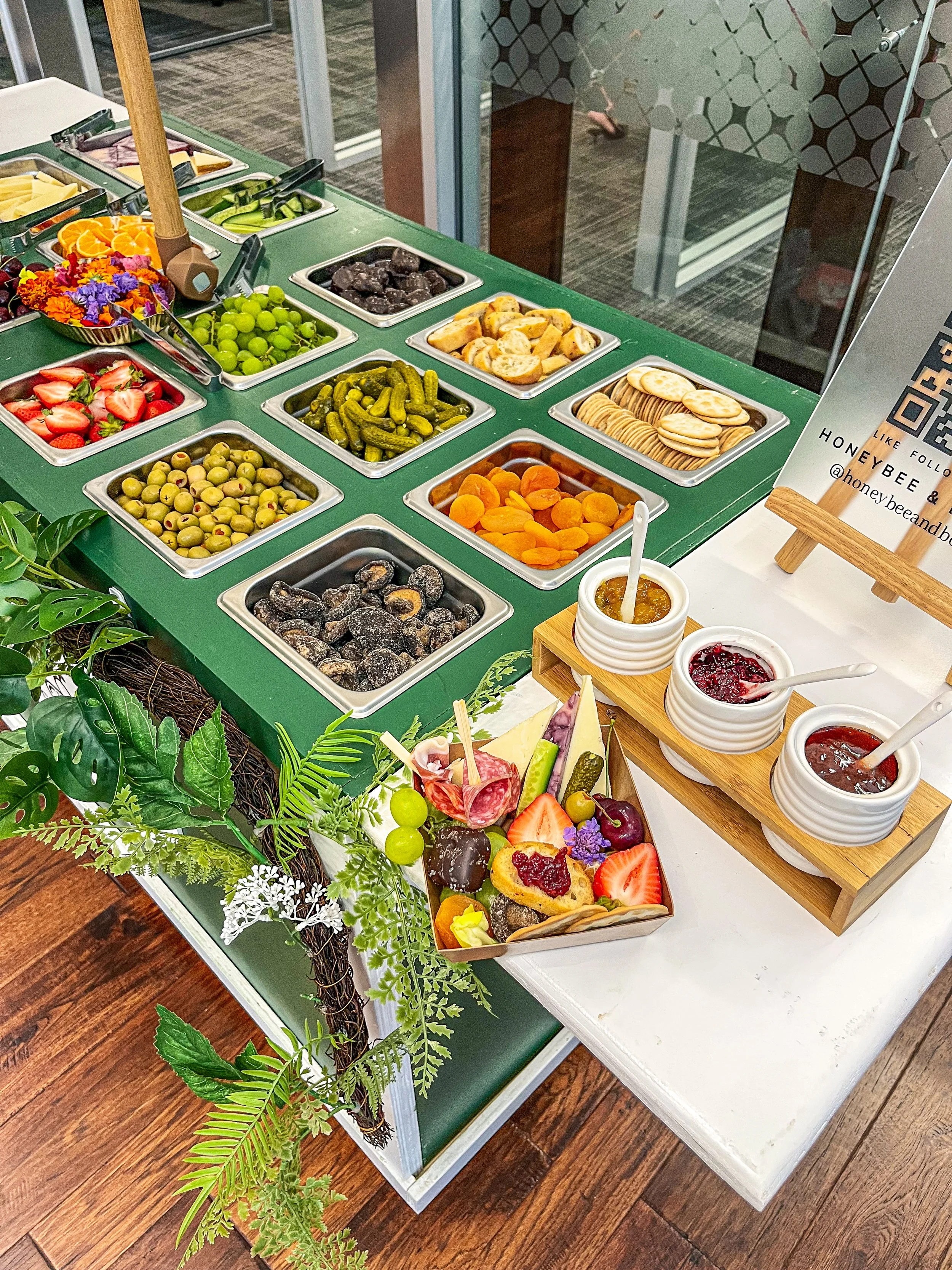 A colorful array of fresh fruit, berries, and various toppings for a dessert or snack setup, with small bowls of sauces and a basket containing strawberries, grapes, and other fruits.