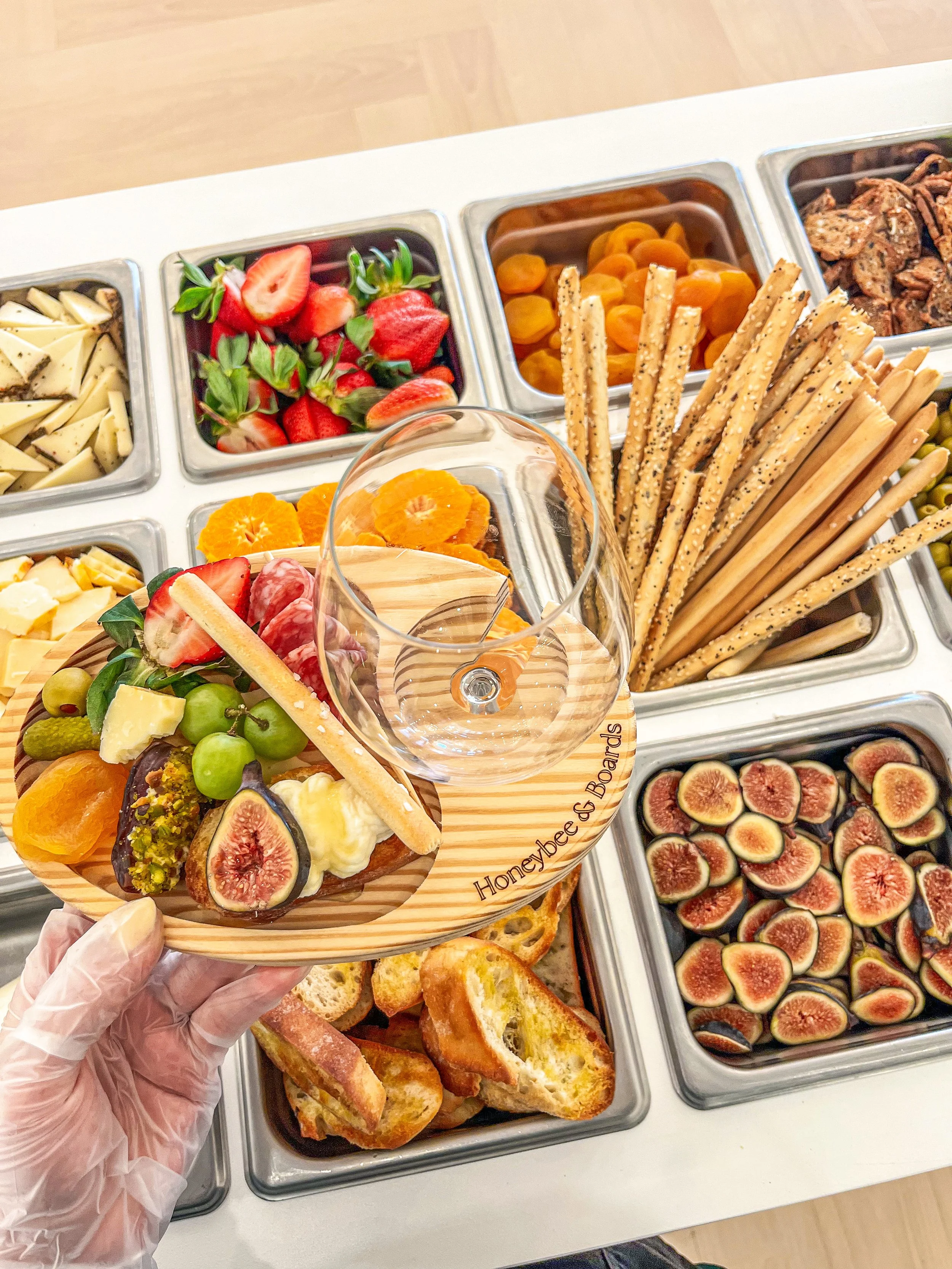 Assorted fresh fruits and appetizers on a wooden tray, including figs, grapes, strawberries, and other fruits.