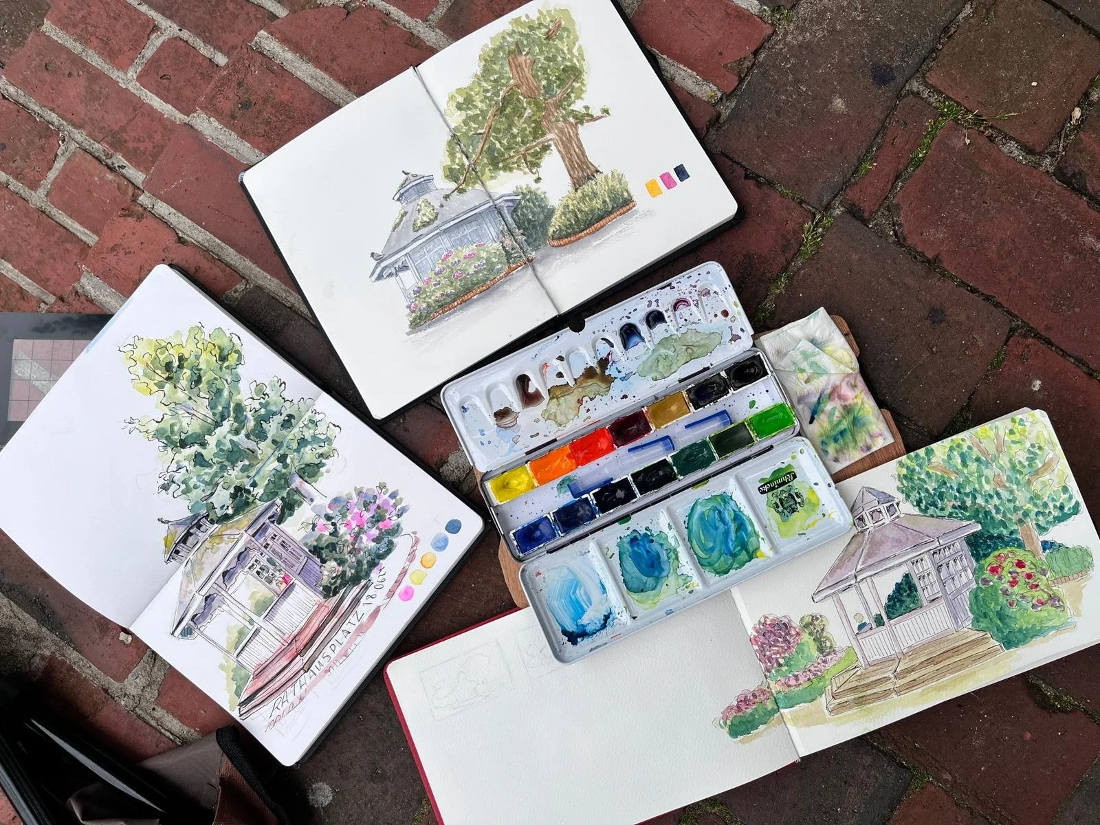 Aquarell-Skizzenbücher und Farben auf Ziegelsteinboden
