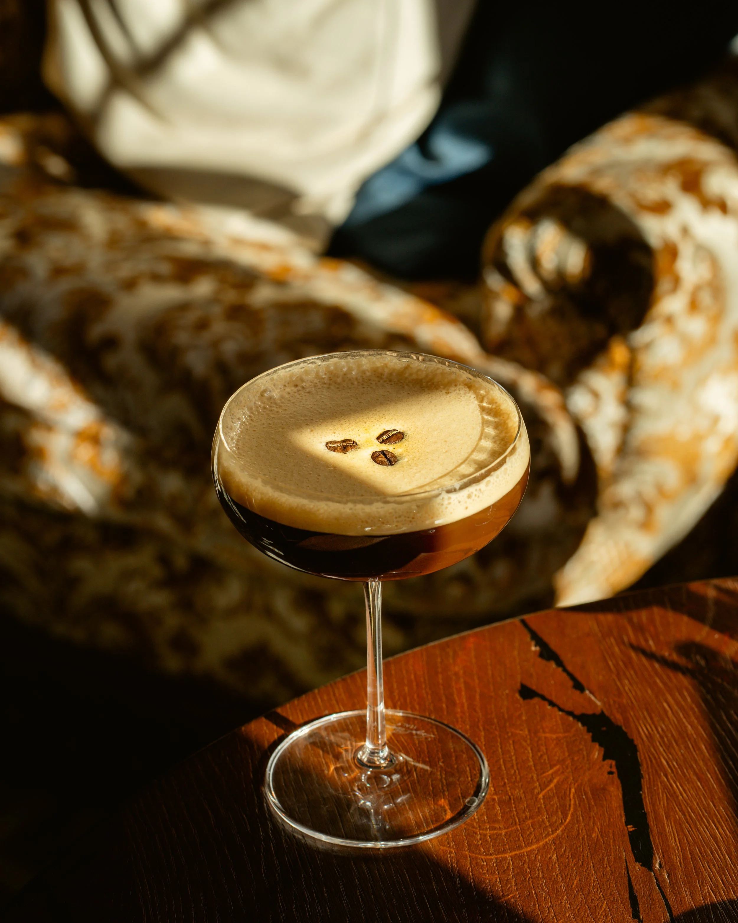 Espresso martini on a wooden table with decorative background.