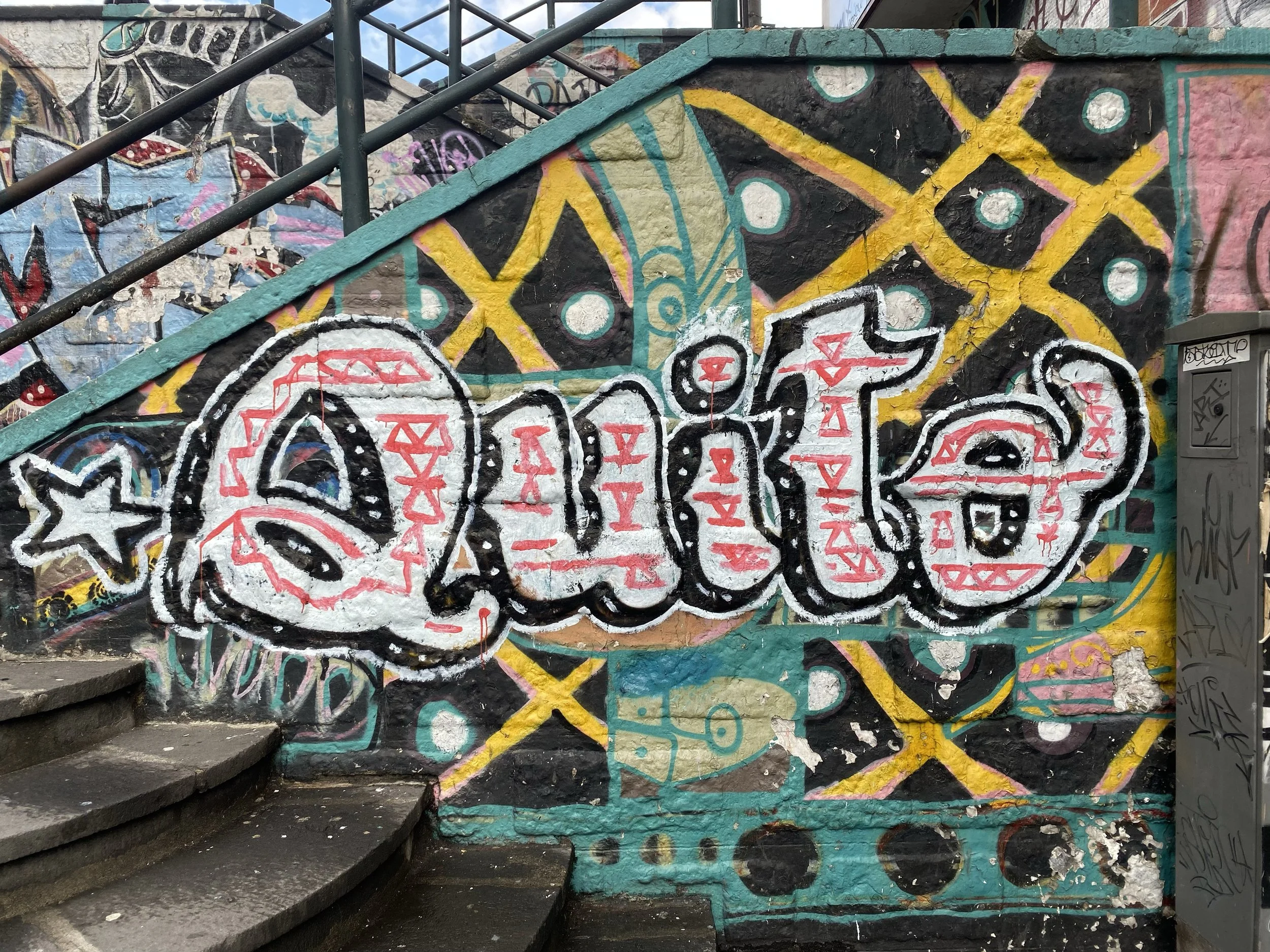 Colorful graffiti art on a wall with the word 'Quito' in stylized letters, surrounded by abstract patterns and designs.