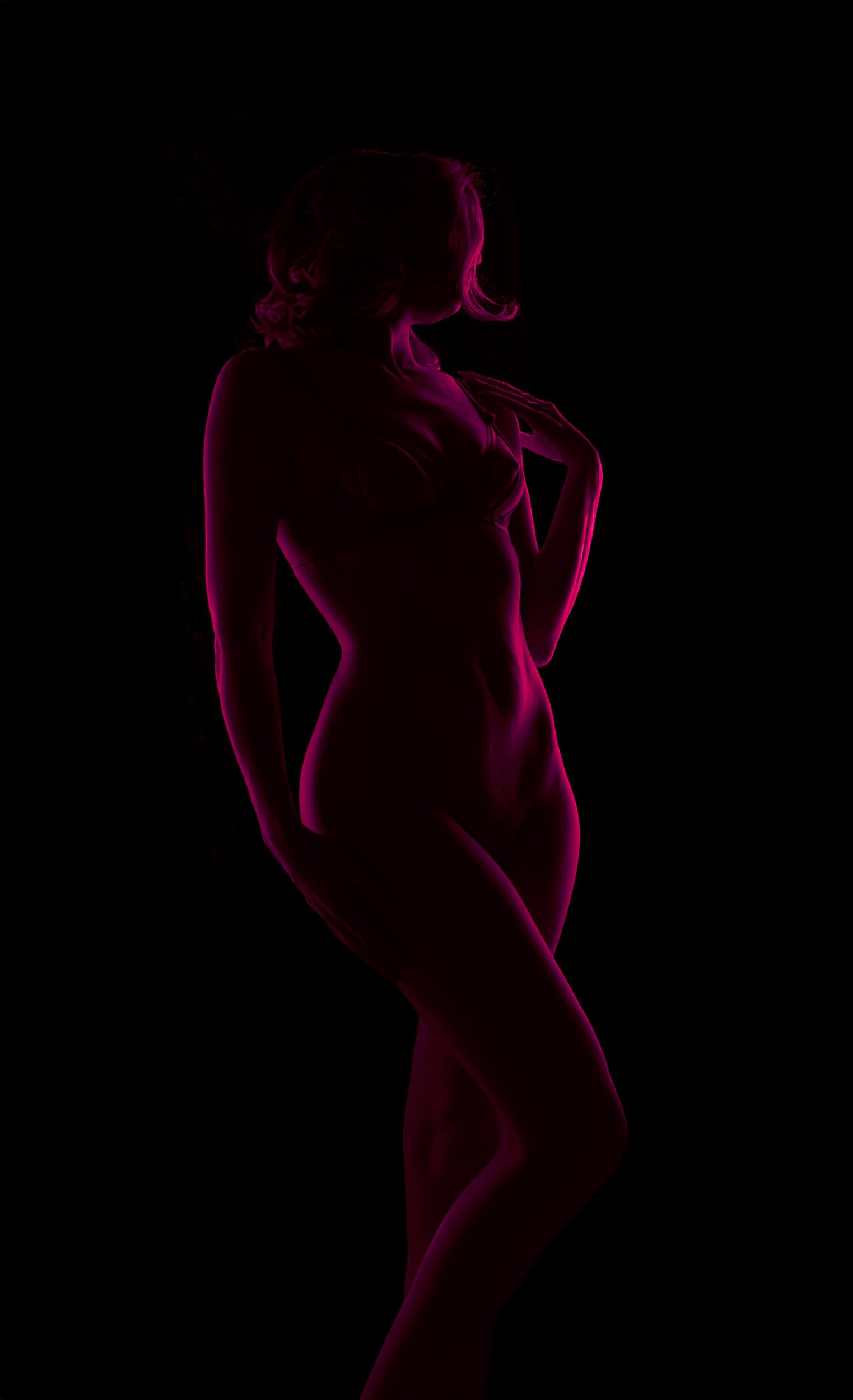 Artistic boudoir silhouette photographed near Portland, Oregon, highlighting body shape with dramatic magenta rim lighting.