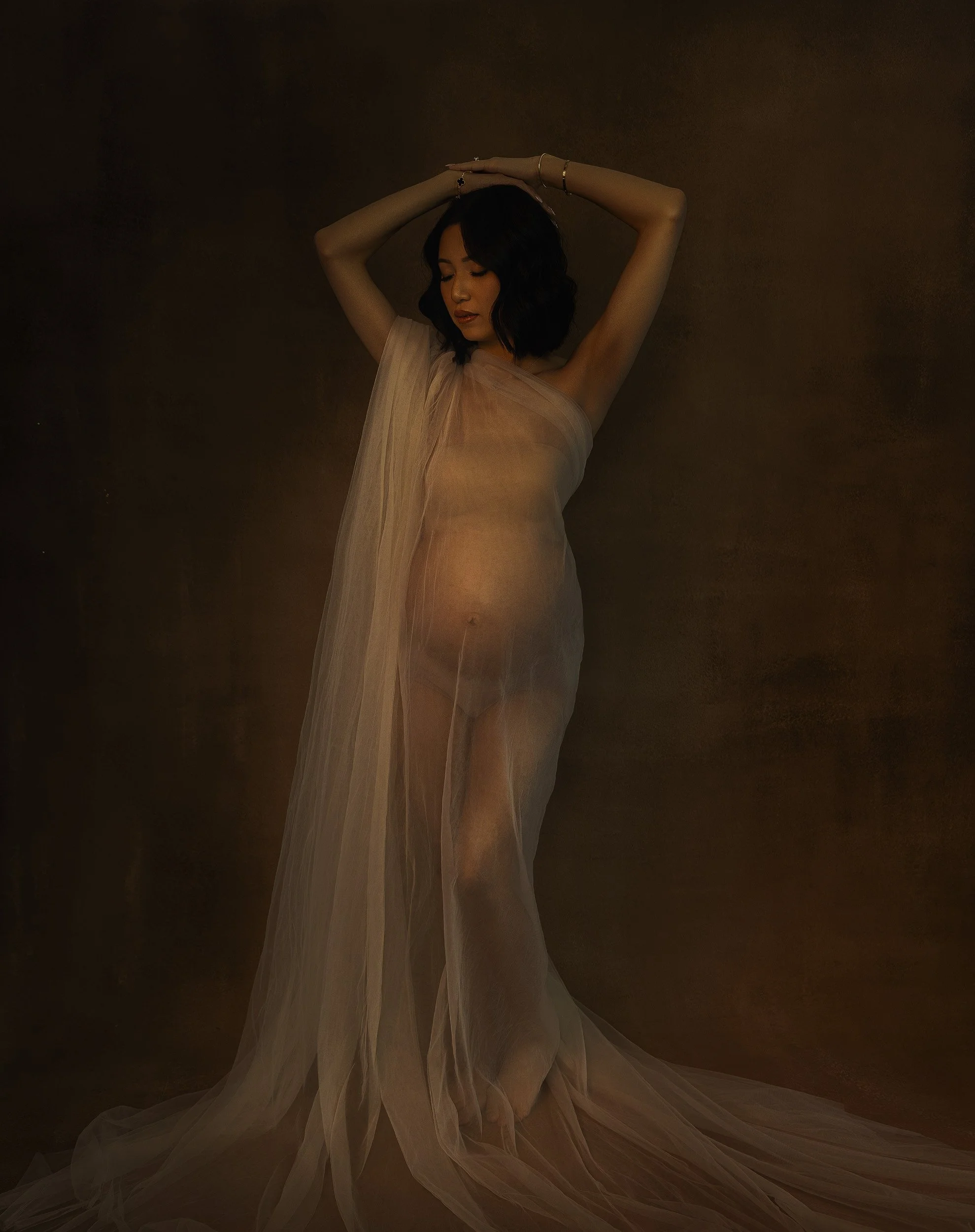 Timeless maternity portrait by Amanda Chantee near Portland, Oregon, featuring a pregnant woman in a soft neutral gown against a warm painterly backdrop.