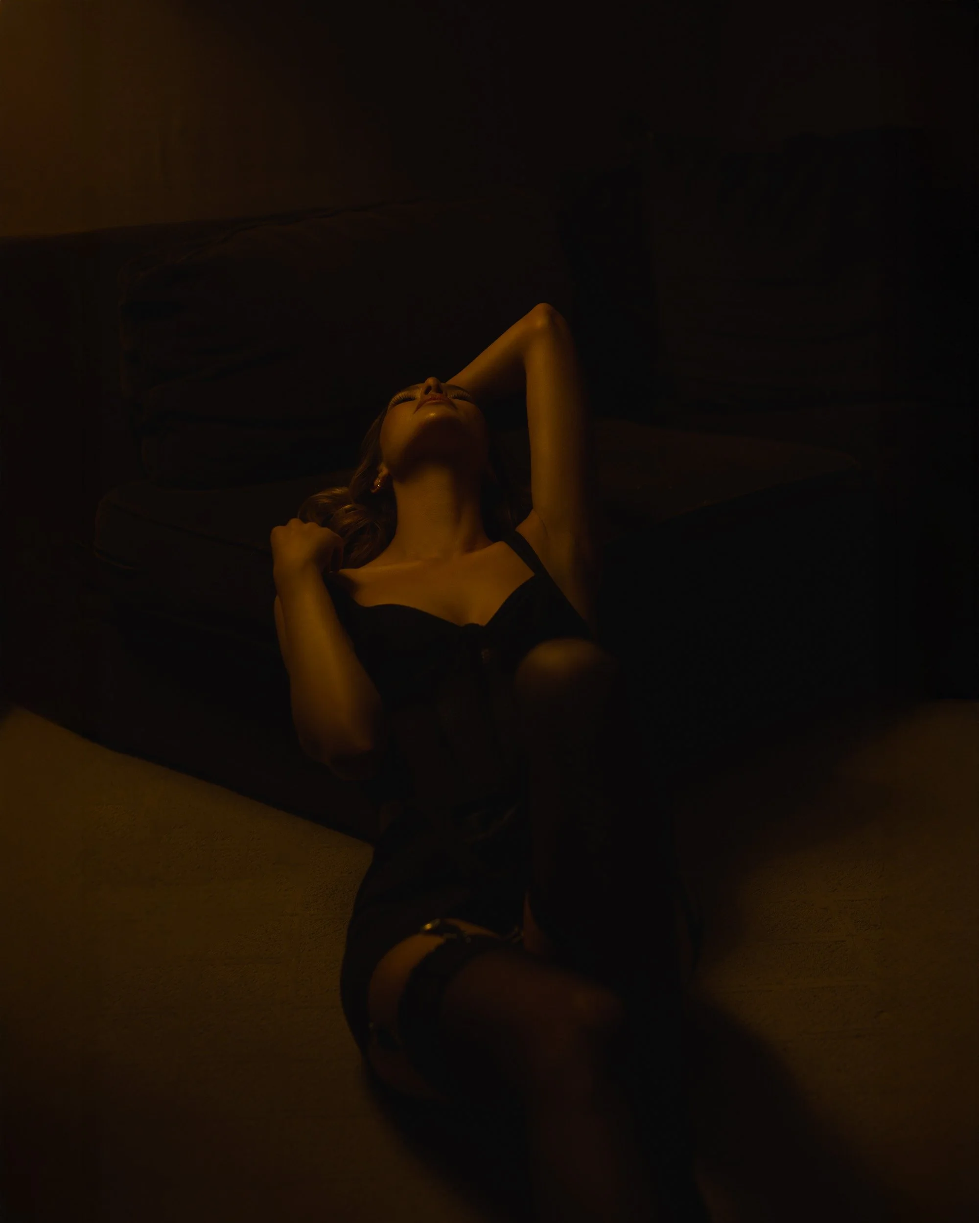 Luxury boudoir photography by Amanda Chantee featuring a woman in black lingerie posing on a bed under dramatic low-key light at The Nines in Portland, Oregon. 