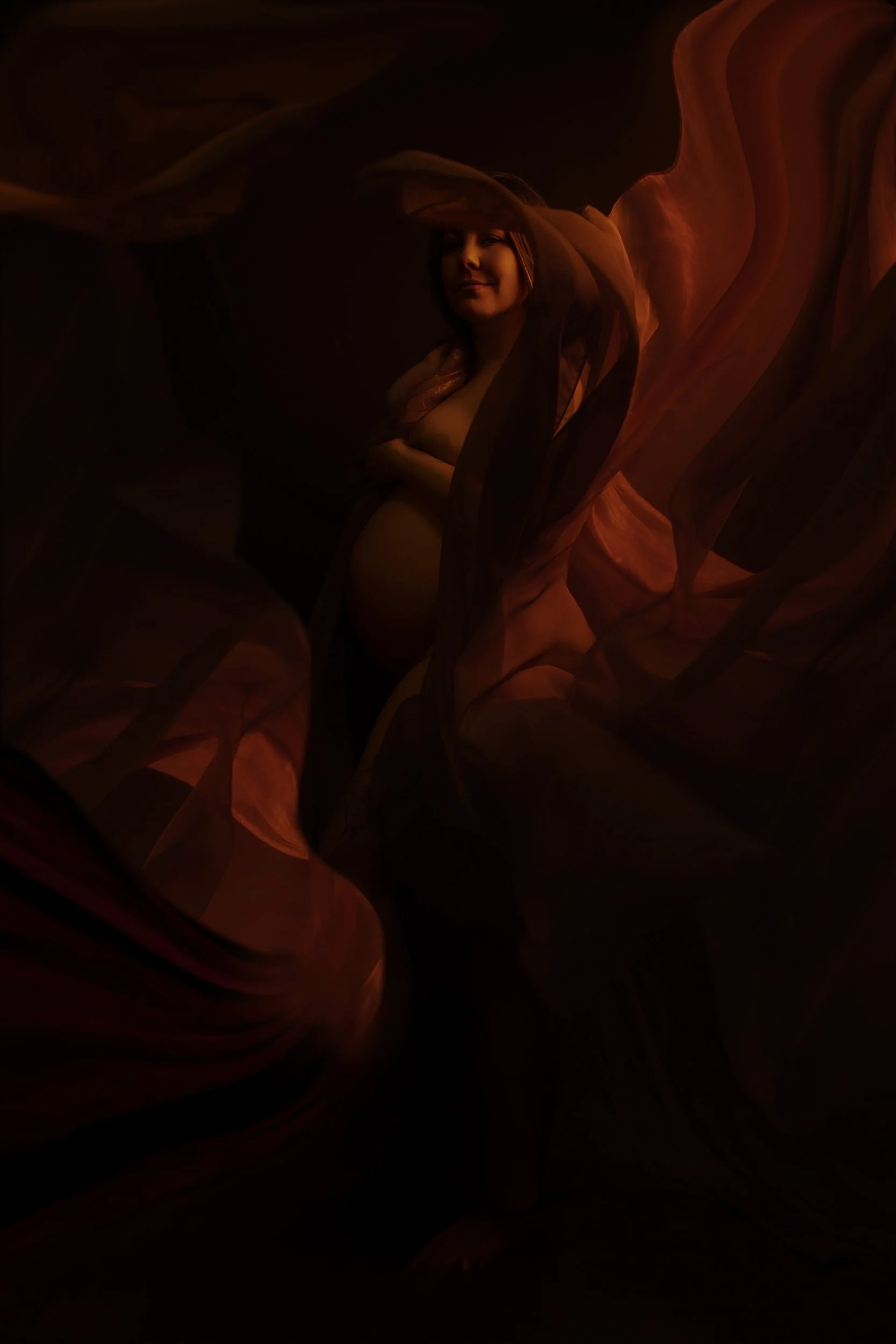 Vancouver WA maternity portrait featuring a pregnant woman surrounded by sweeping copper fabric under warm cinematic studio light.