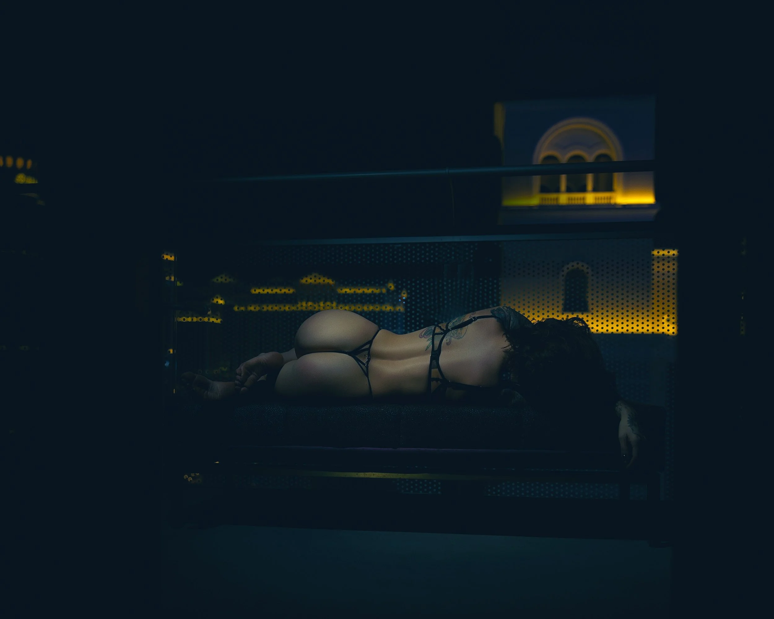 Luxury hotel boudoir portrait near Portland, Oregon, featuring a woman reclining in black lingerie with moody city-view lighting.