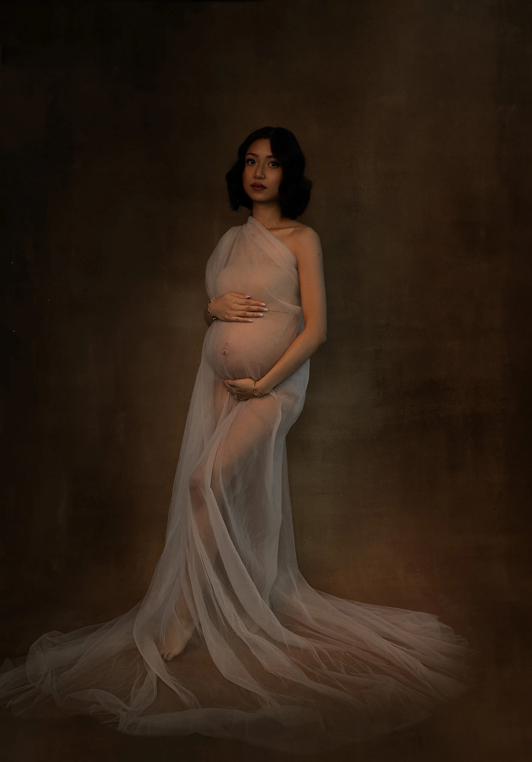 Close-up fine art maternity portrait in Vancouver, WA, highlighting the curves of pregnancy under dramatic magenta and shadowed studio lighting.