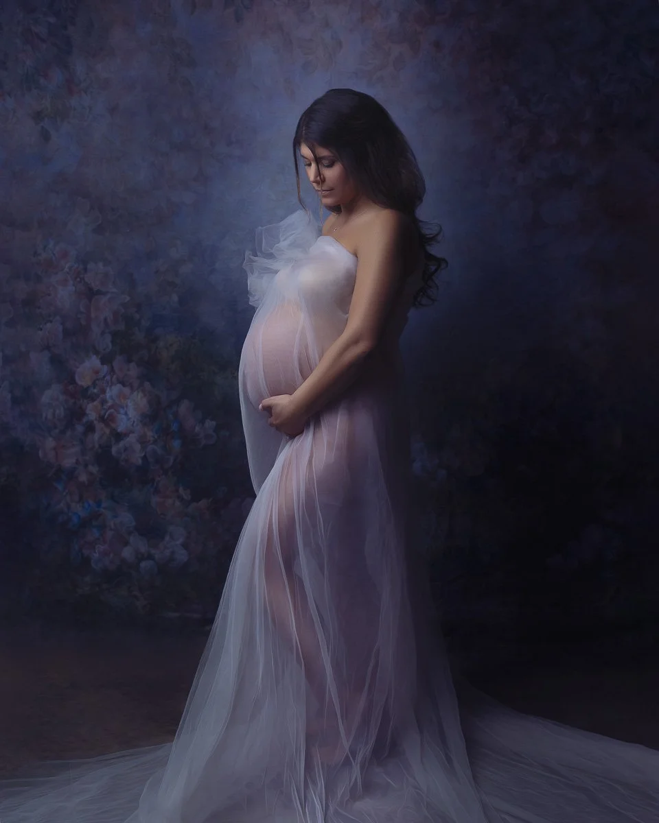 Fine art maternity portrait by Amanda Chantee in Vancouver, WA, featuring a pregnant woman in a sheer lavender gown against a painterly floral backdrop.