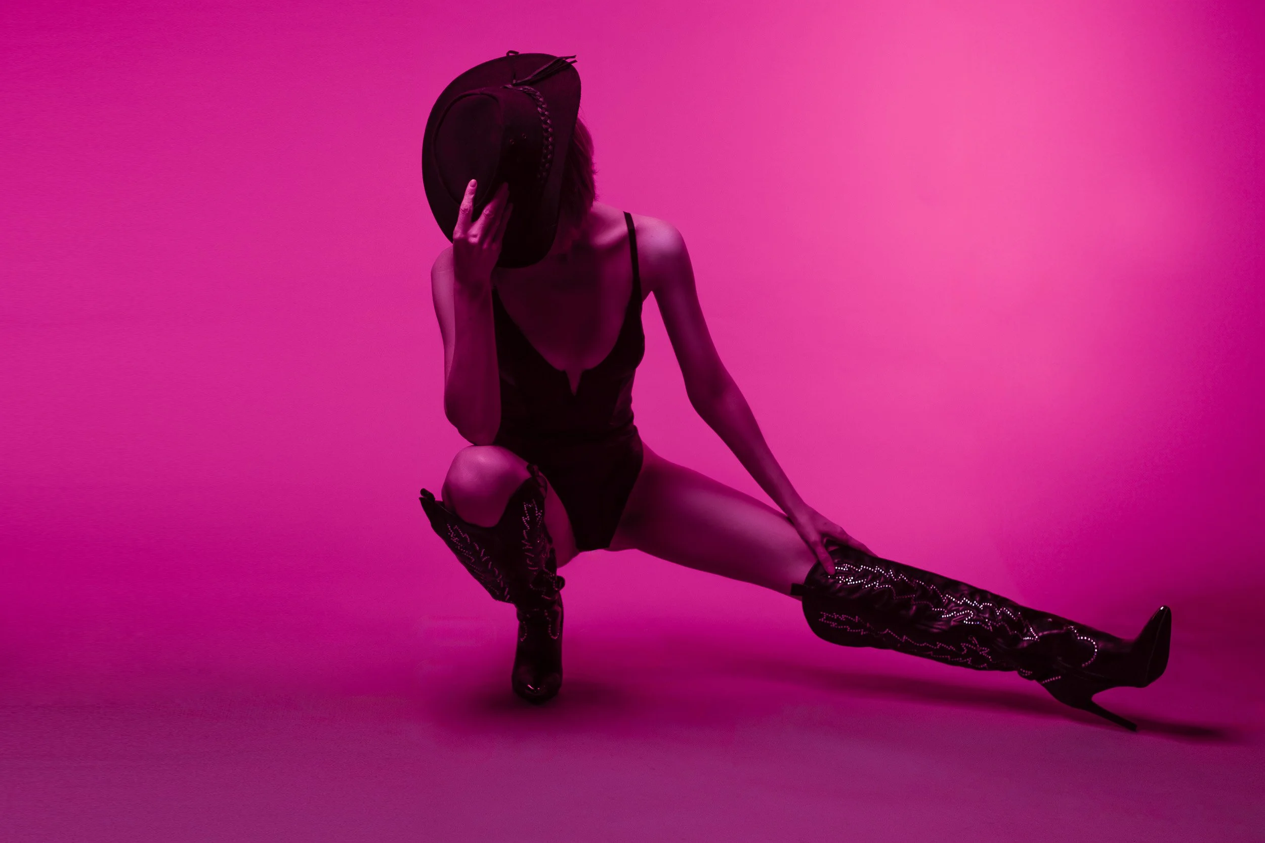 Luxury boudoir portrait near Portland, Oregon, featuring a woman in black lingerie and layered body chains under teal and amber studio lighting.