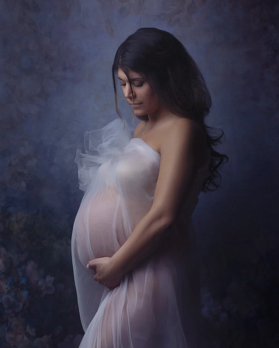 Soft maternity portrait near Portland, Oregon, featuring a pregnant woman wrapped in sheer white fabric against a painterly floral backdrop.
