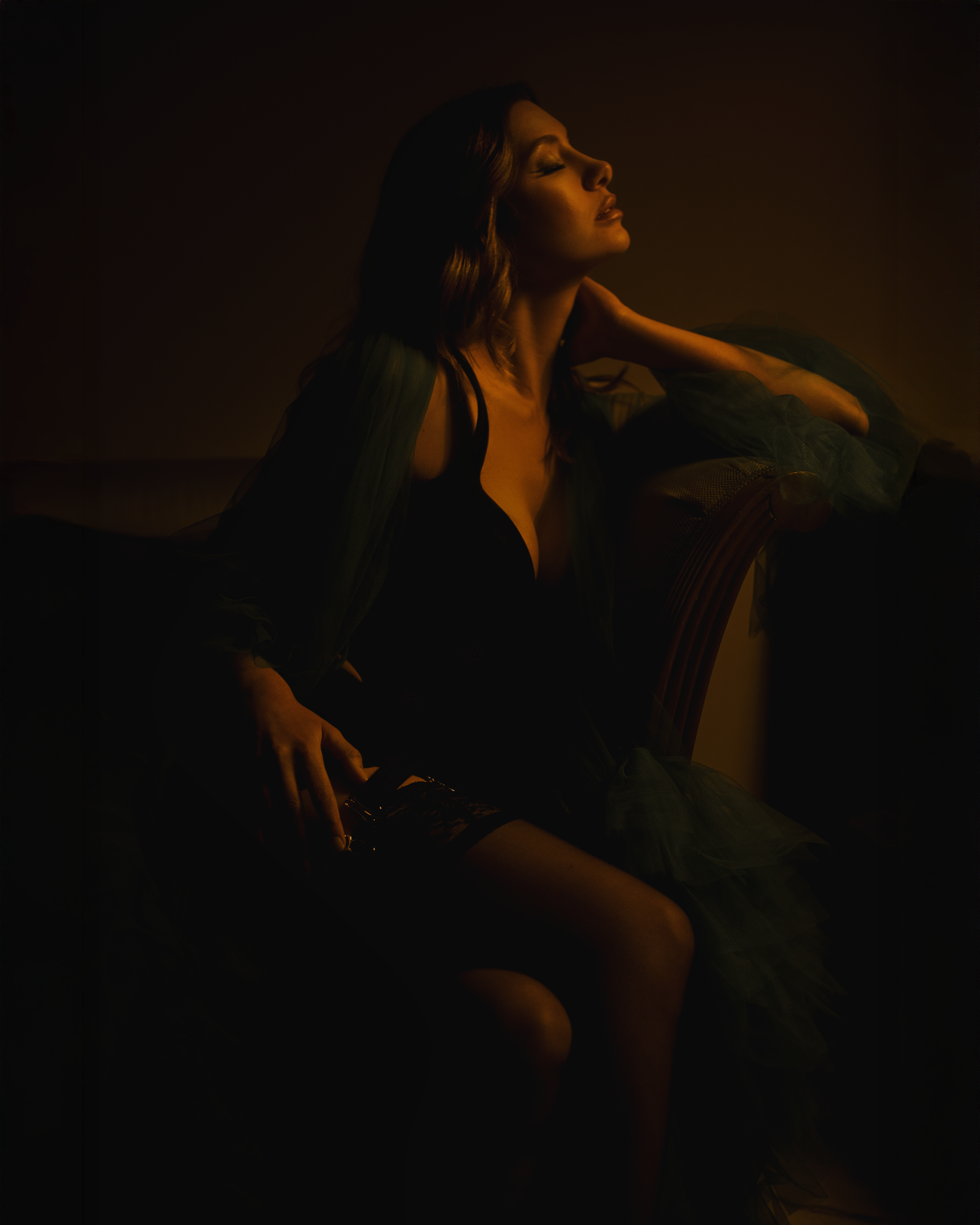 Las Vegas boudoir portrait of a woman in warm bronze studio lighting, seated on a bench by Amanda Chantee.