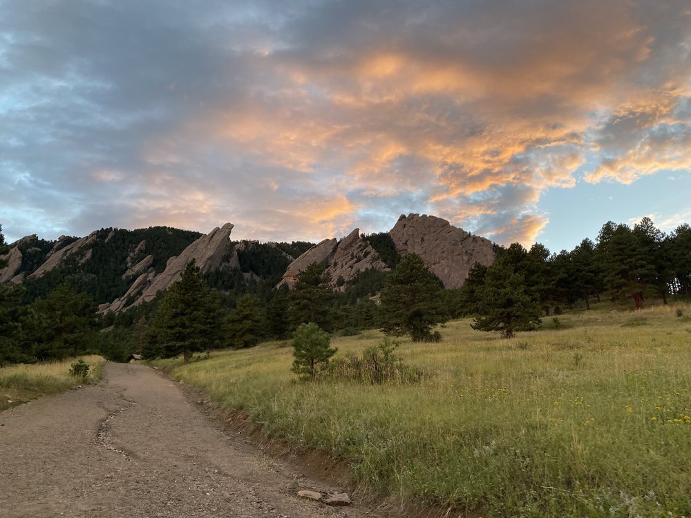 Flatirons at sunset above a trail and meadow in Boulder