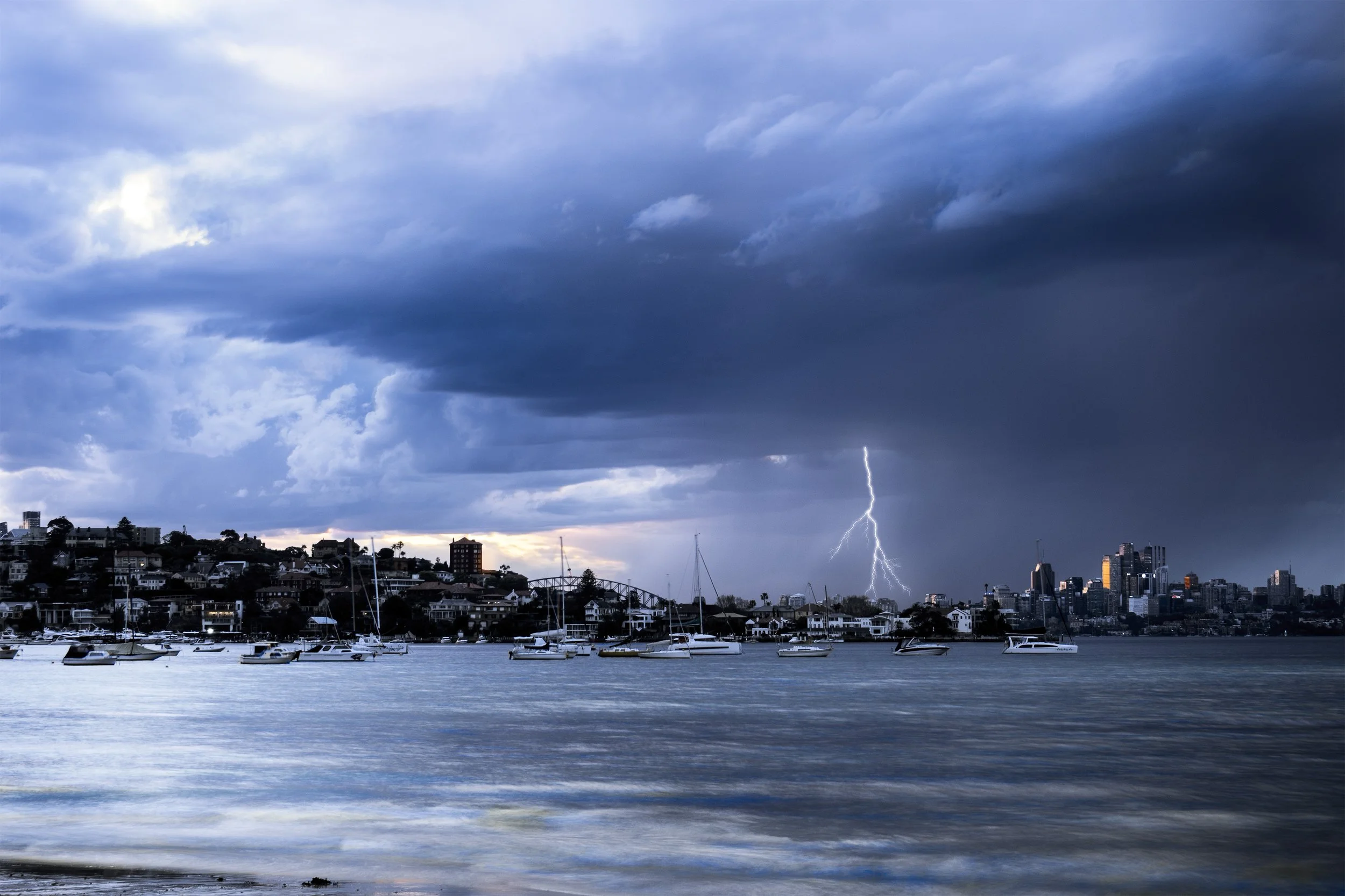 A cinematic time-slice of Sydney’s skyline as night gives way to dawn, captured from Rose Bay with the moon hanging over the city and light trails stretching into the sky. Perfect for lovers of urban landscapes and moody coastal views, this piece bri