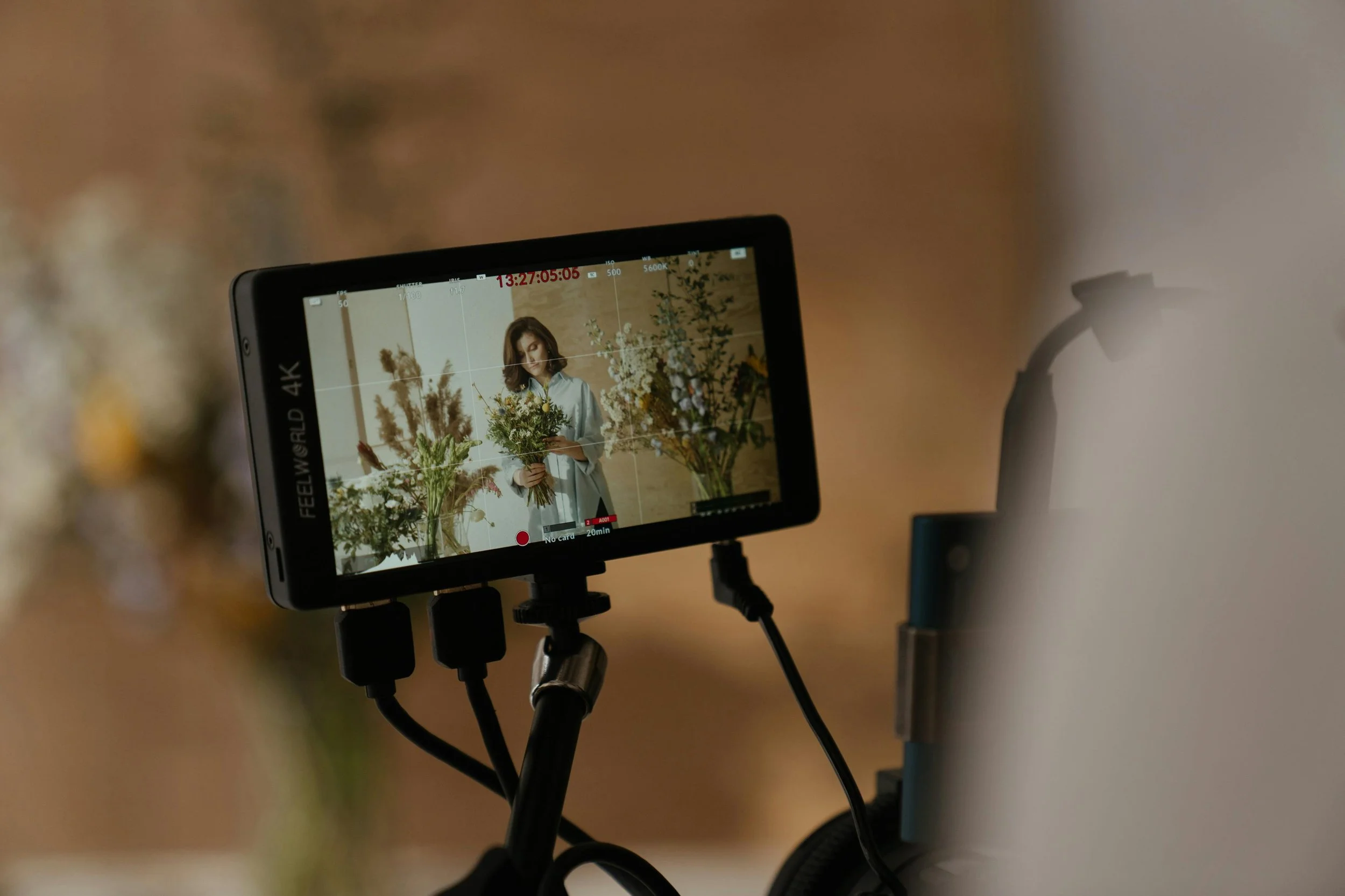 A woman arranging flowers in a studio with a professional camera recording the process.