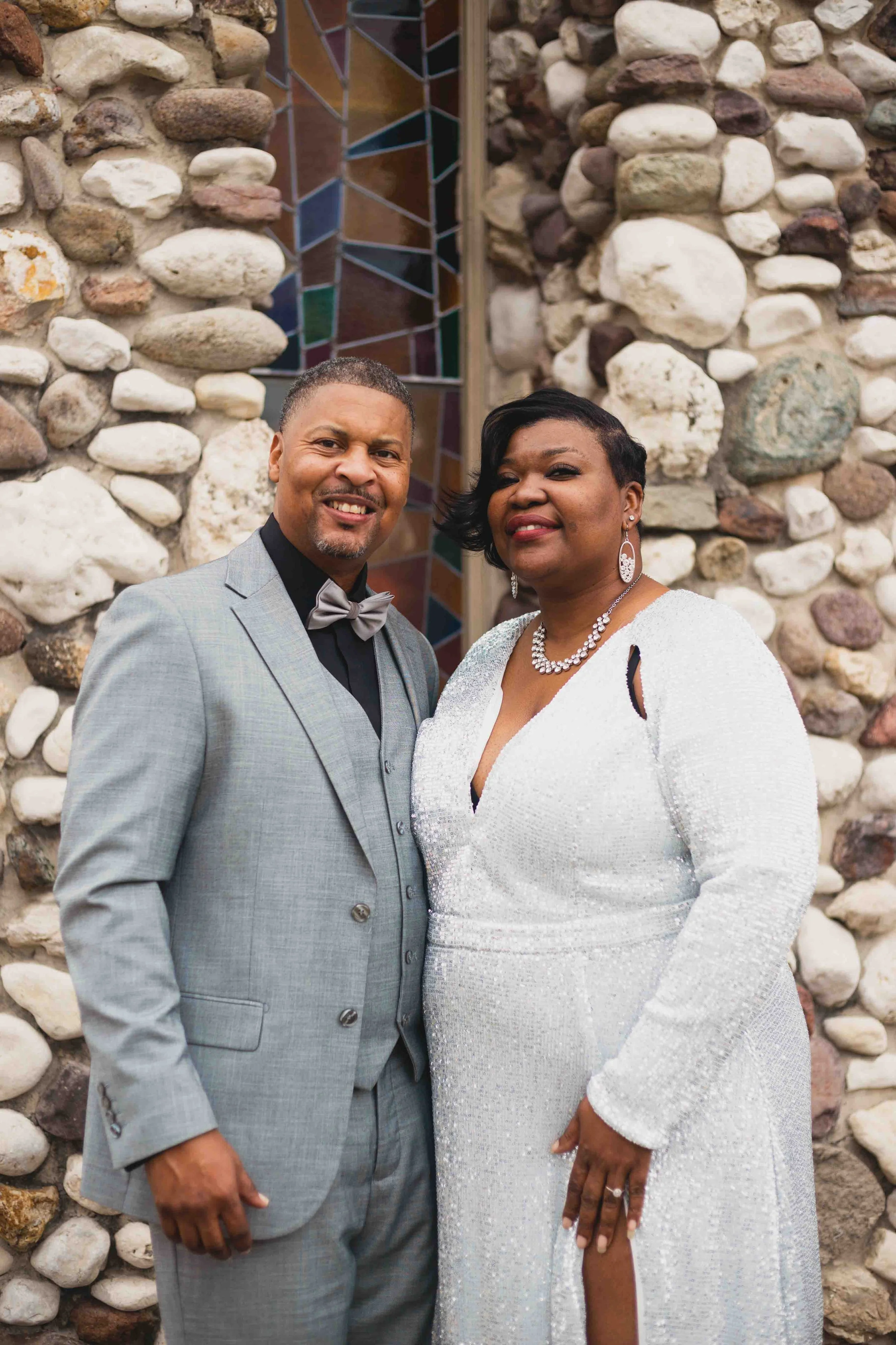 Formal couple portrait in Houston, Texas by Lev’s Photography featuring a smiling couple dressed in elegant attire standing in front of a stone and glass wall