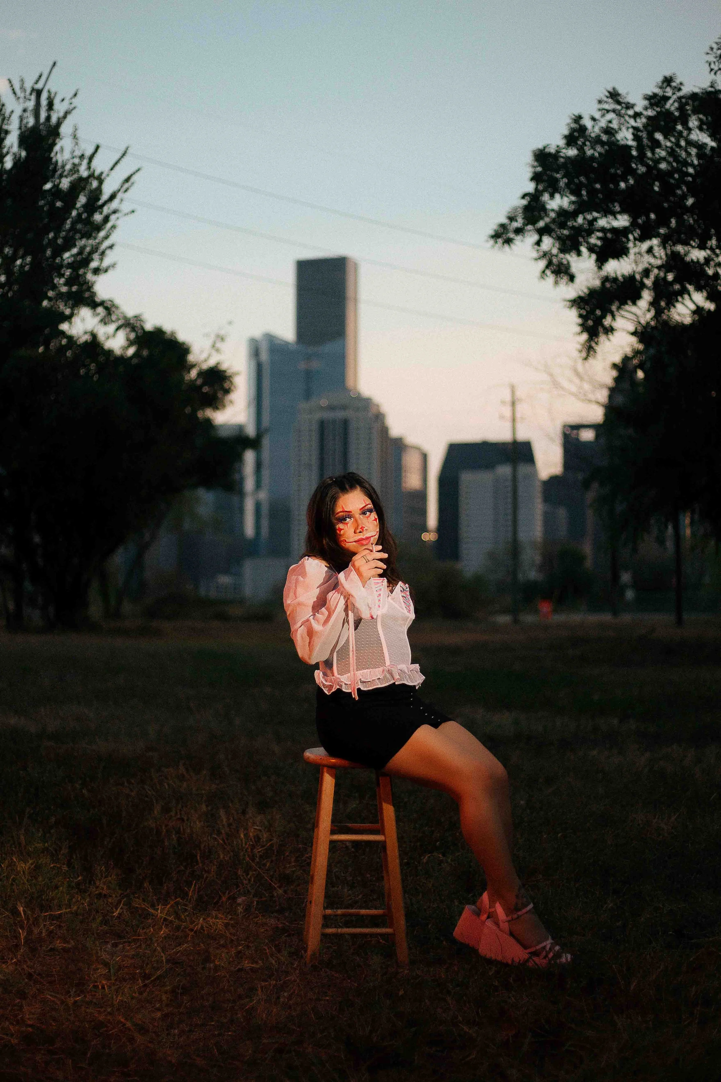 Cinematic portrait of a subject wearing dramatic clown makeup in a downtown urban setting with moody city lighting