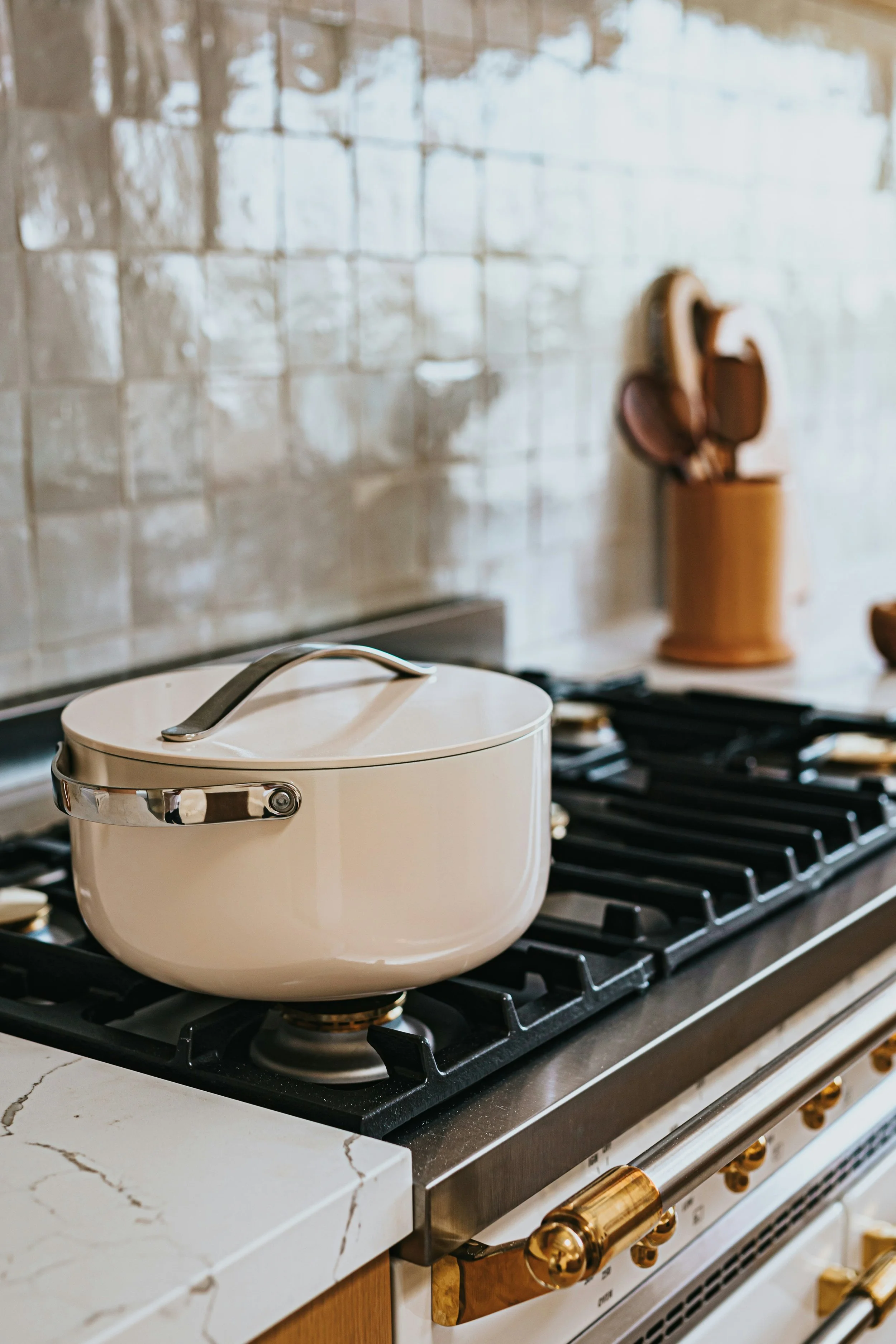 Elegant kitchen stove featuring high-end gold accents with earth-tone square zellige tiles as the backsplash. I'm not a great cook but I'll happily stop by for taste testing in this gorgeous new kitchen!