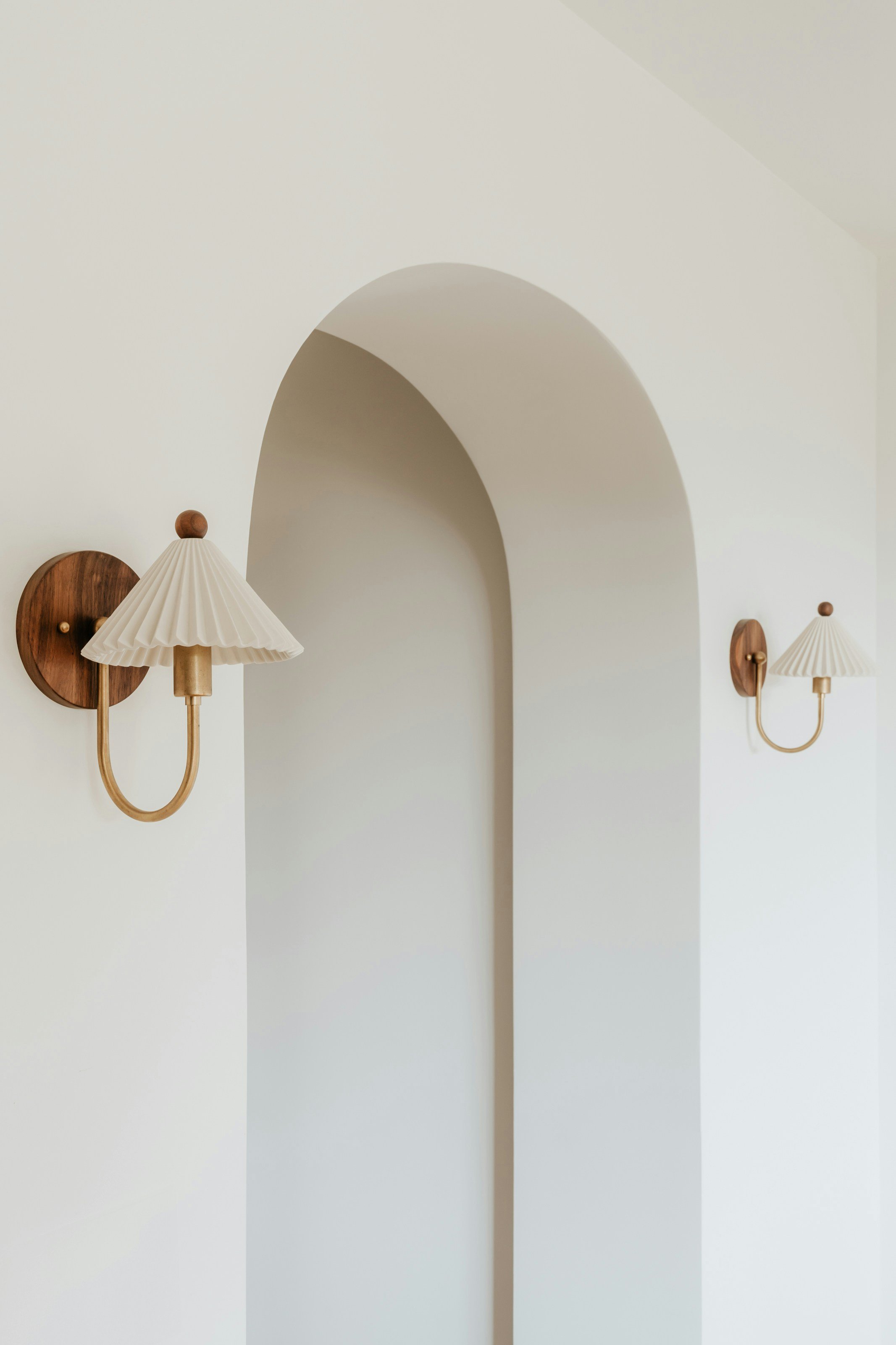Elegant white wall adorned with unique light fixtures on each side, creating a modern and sophisticated ambiance while highlighting the clean lines and simplicity of the space.