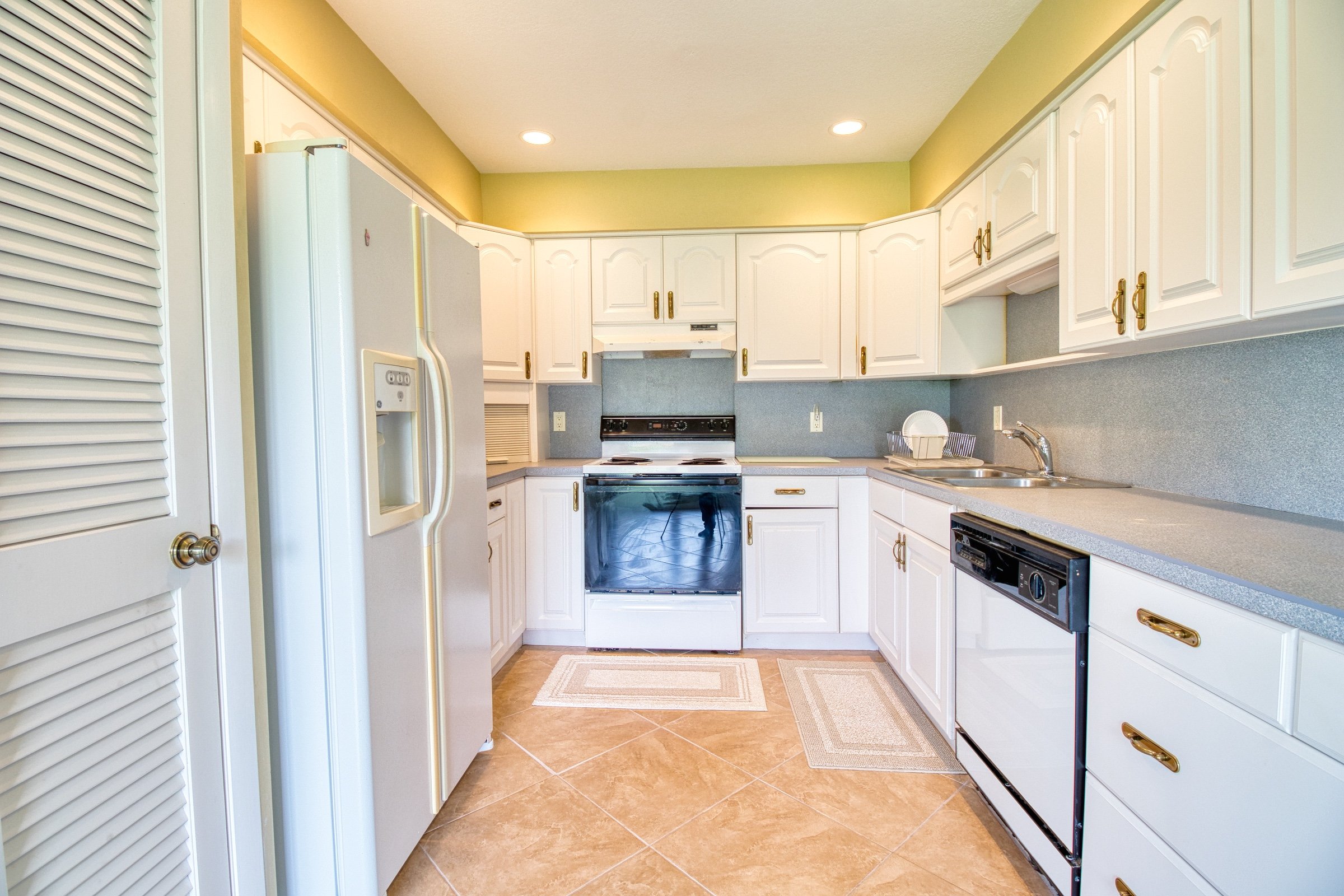 Bright kitchen with white cabinets, stainless steel appliances, and beige tile flooring