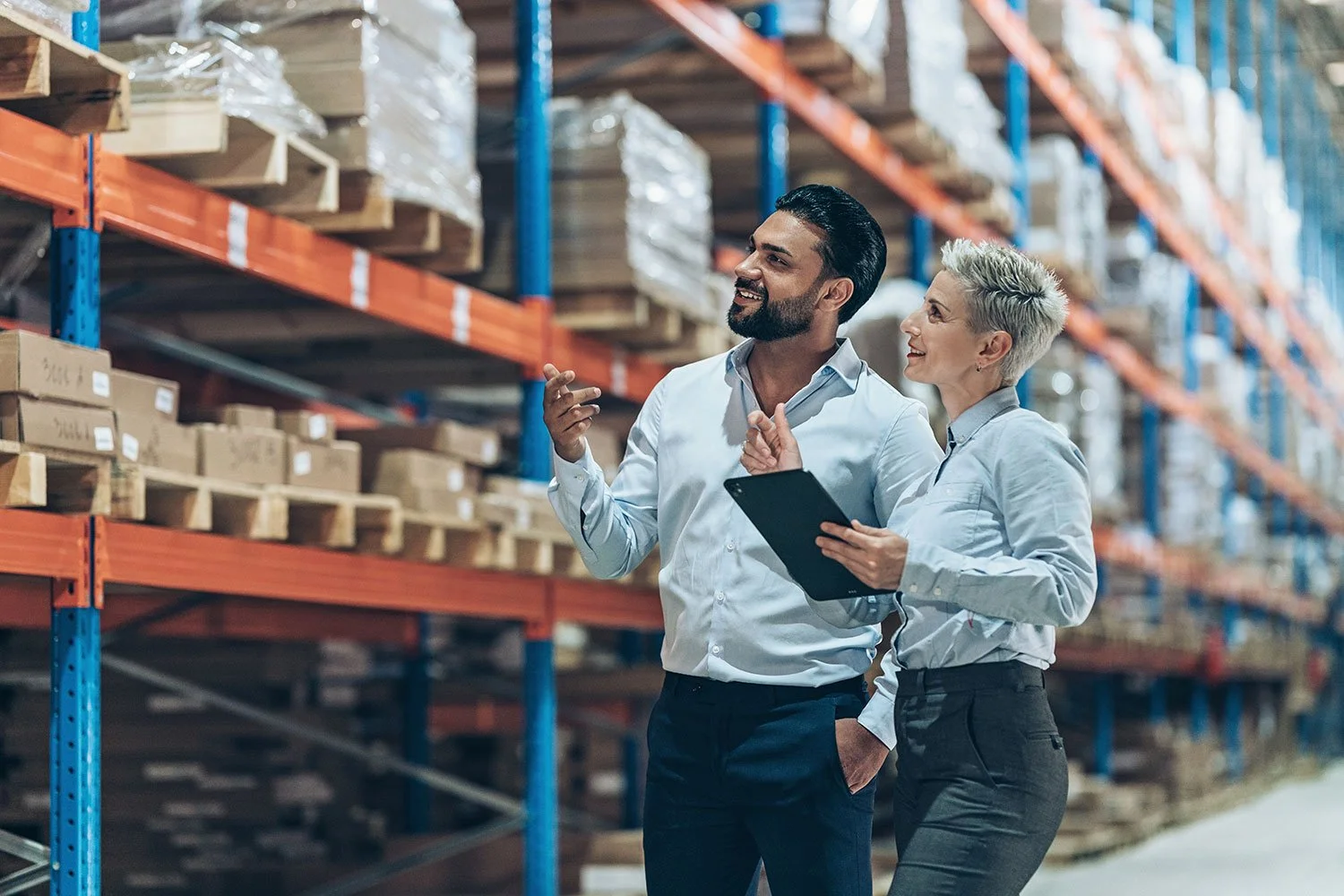 Confident supplier talking with customer about products in warehouse setting