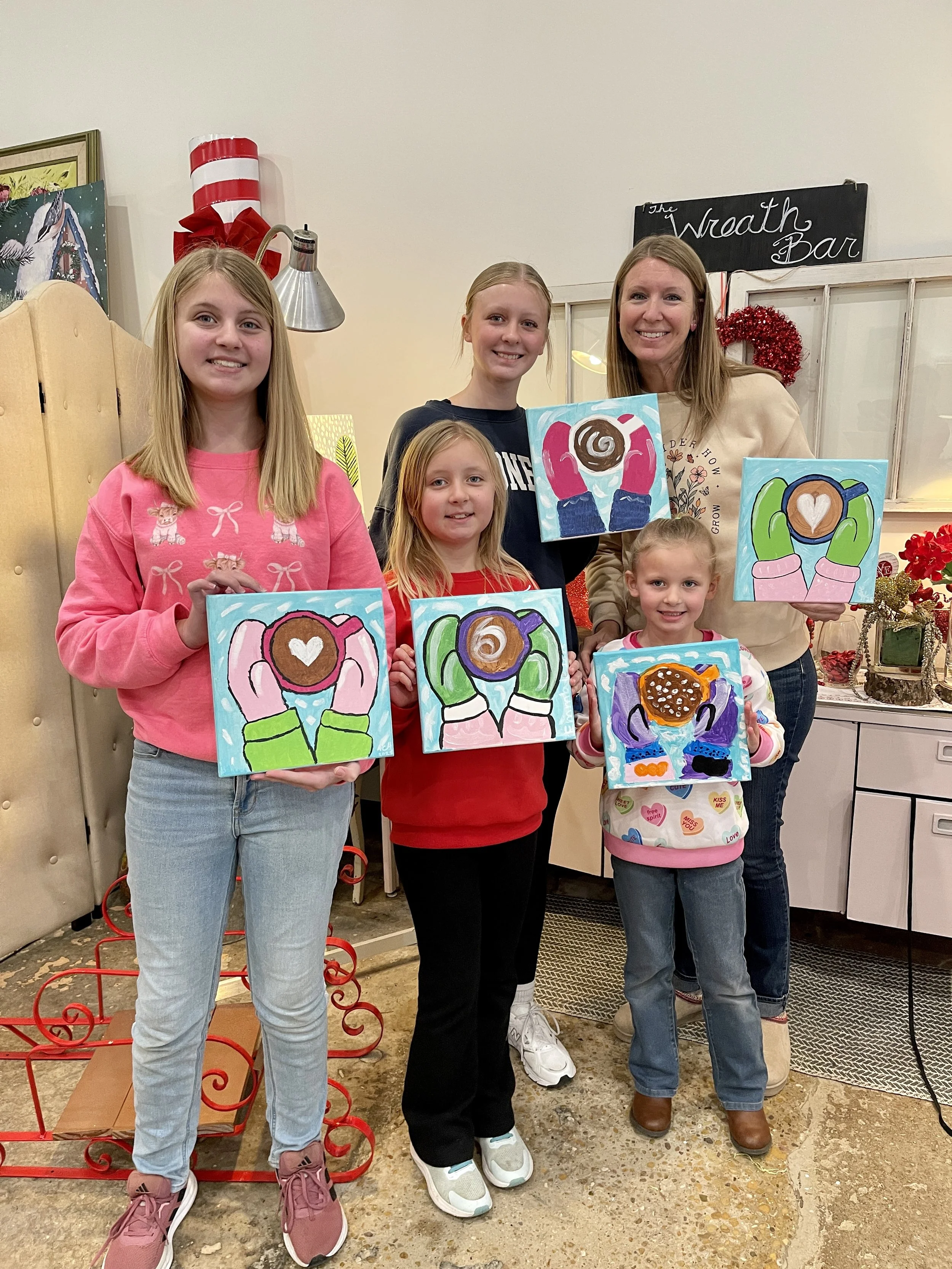 Group of five females holding canvas paintings of hands holding coffee cups.