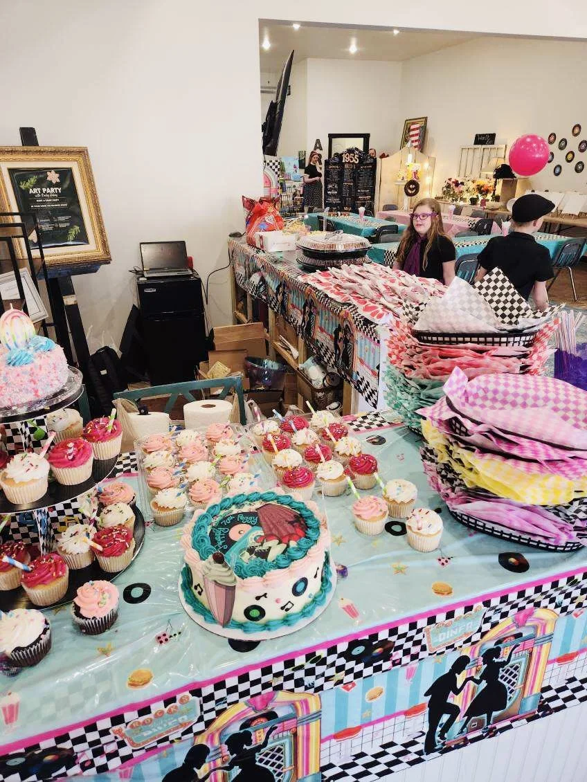 Colorful dessert table at a birthday party with cupcakes, a themed cake, party hats, and decorations.