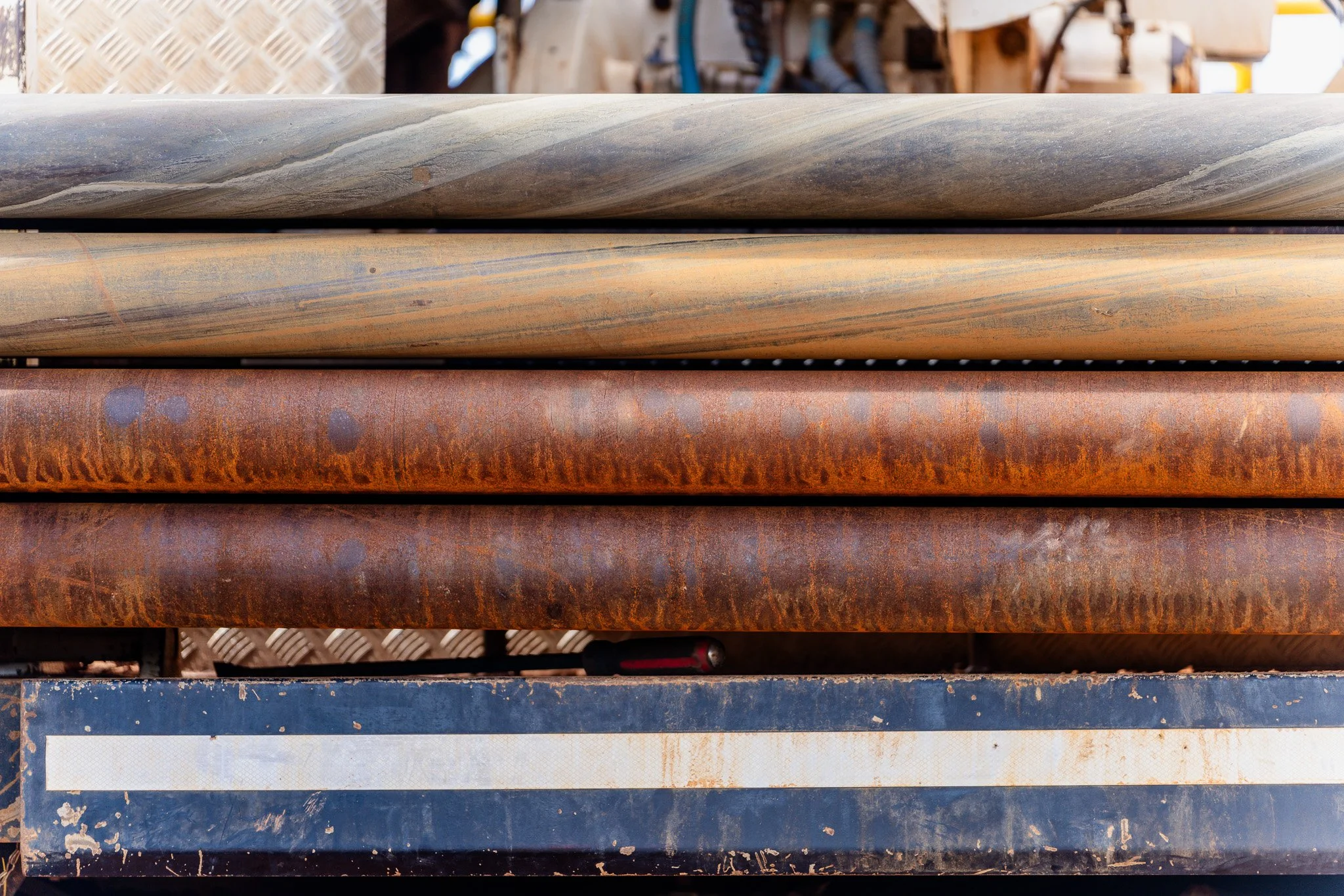 Stacked metal pipes with rust and weathering in an industrial setting.
