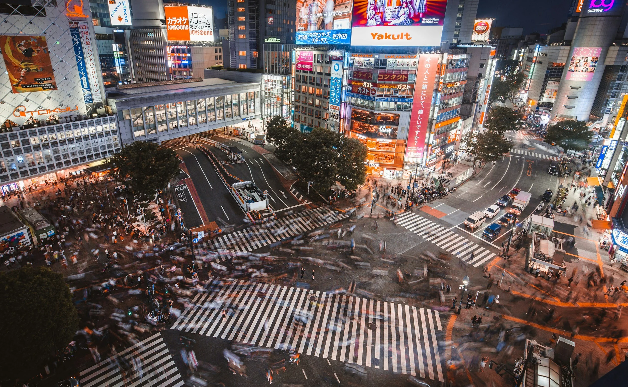 Photo of Shibuya Crossing in Tokyo at night with hundreds of people in the street.