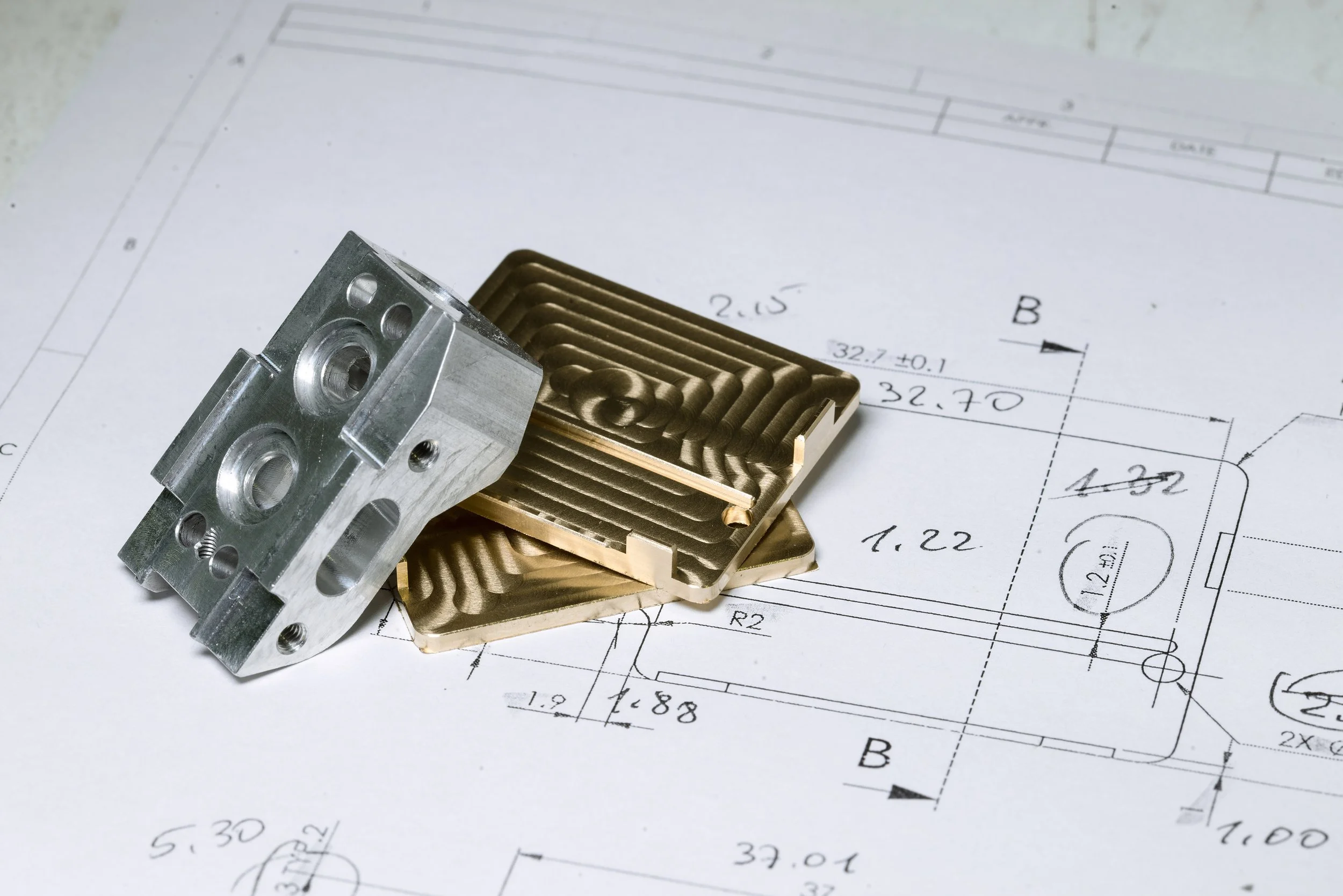 Mechanical parts placed on technical engineering drawings with measurements and annotations.
