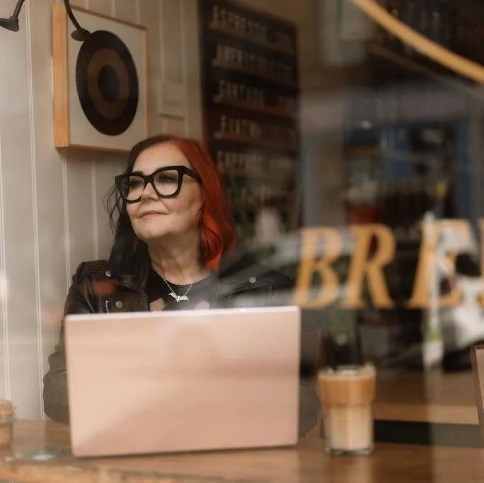 Image shows author Helen Phifer with a laptop in a coffee shop