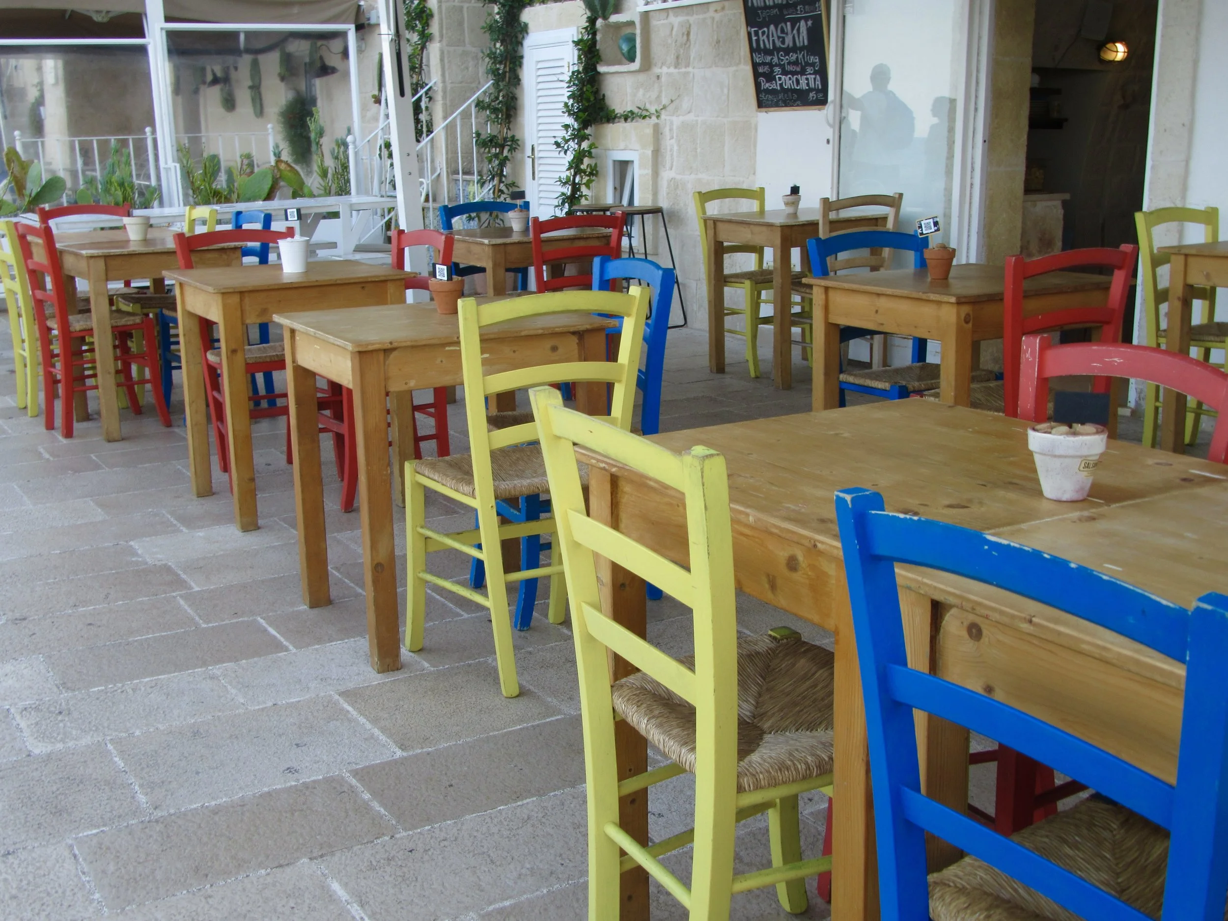 Colorful outdoor seating at a seaside restaurant in Monopoli, Puglia.