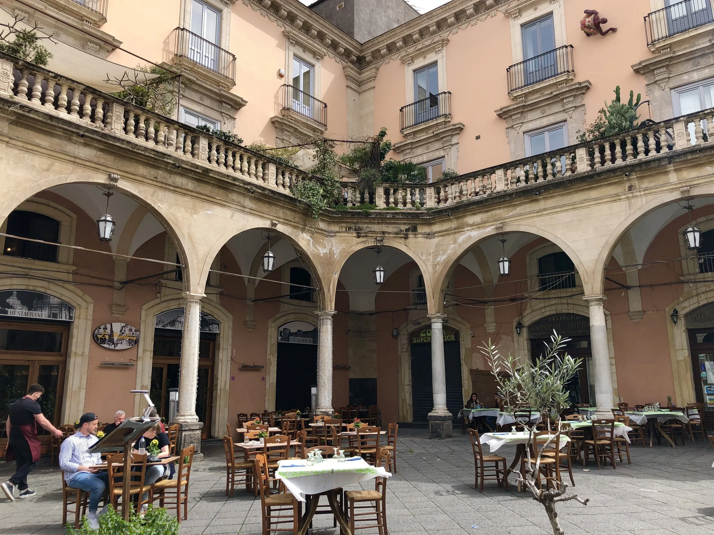 A beautiful building and outdoor restaurant seating in Catania, Sicily.