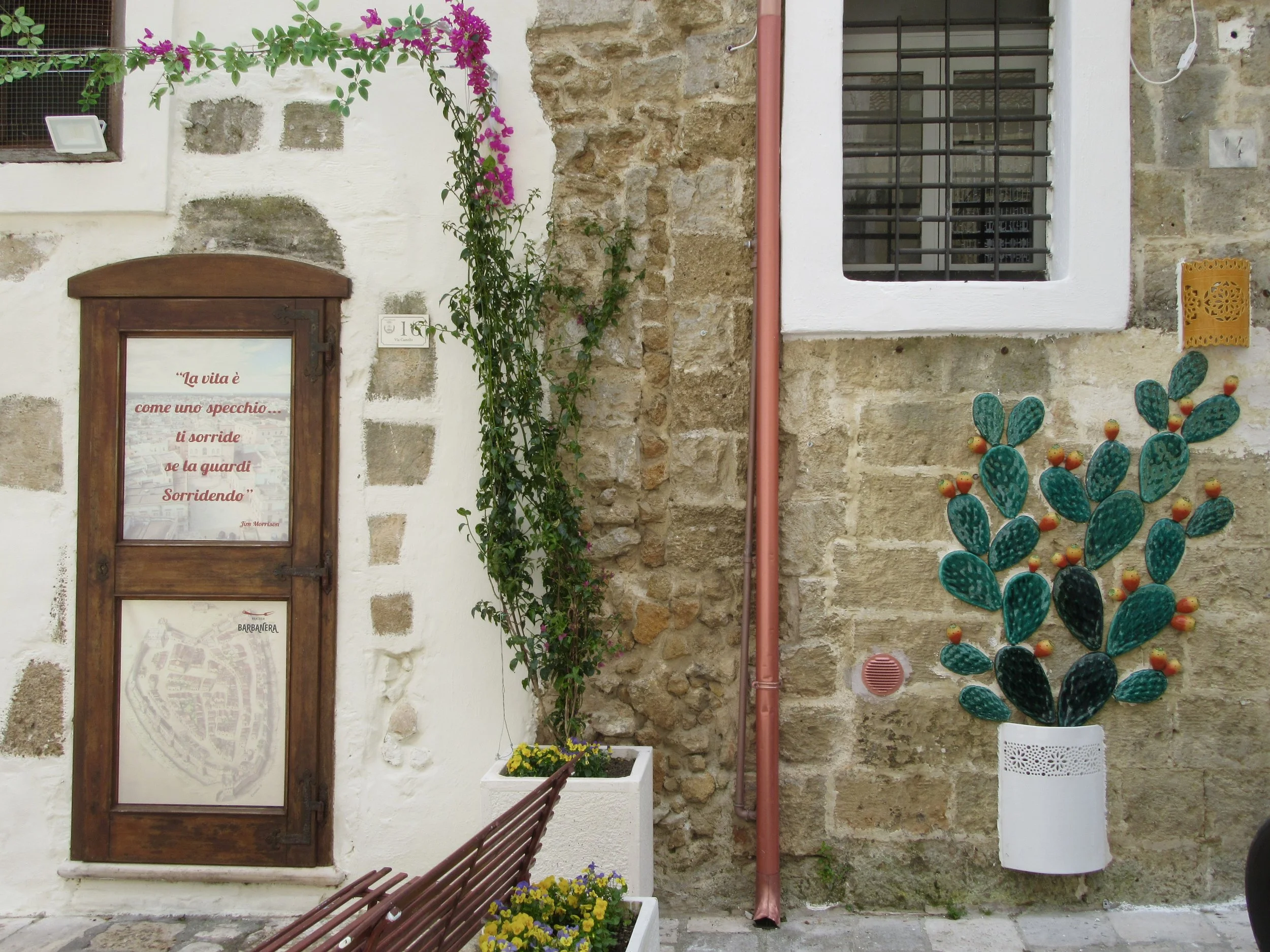 A doorway and a decorative ceramic cactus against a stone wall in Mesagne, Puglia.