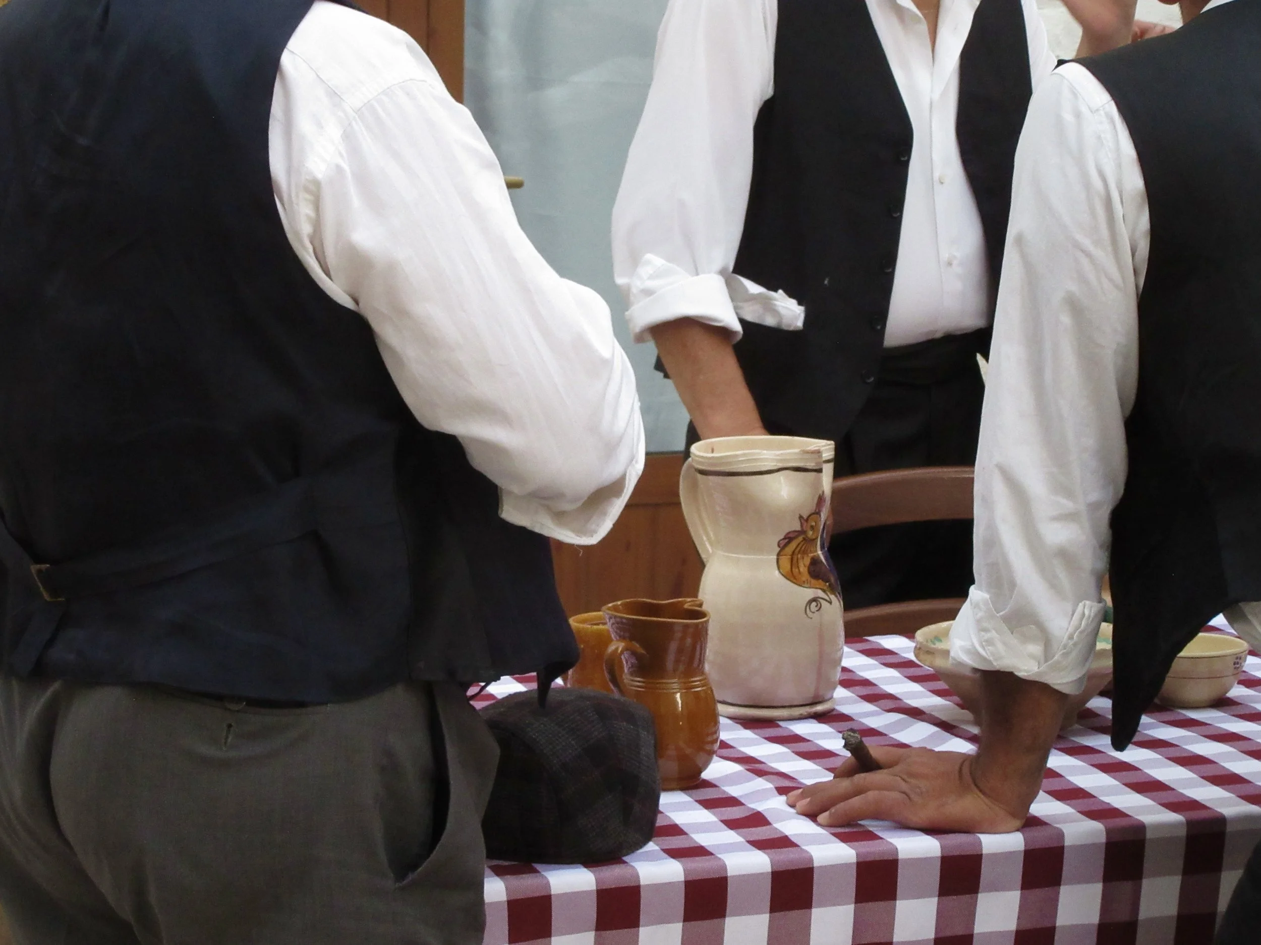 Three men standing around a table with a checkered tablecloth in Locorotondo, Puglia.