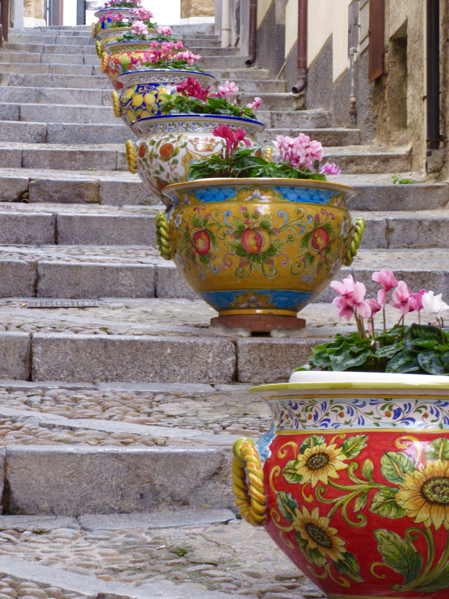 Ceramic flower containers filled with flowers line a stairway in Cefalu, Sicily.