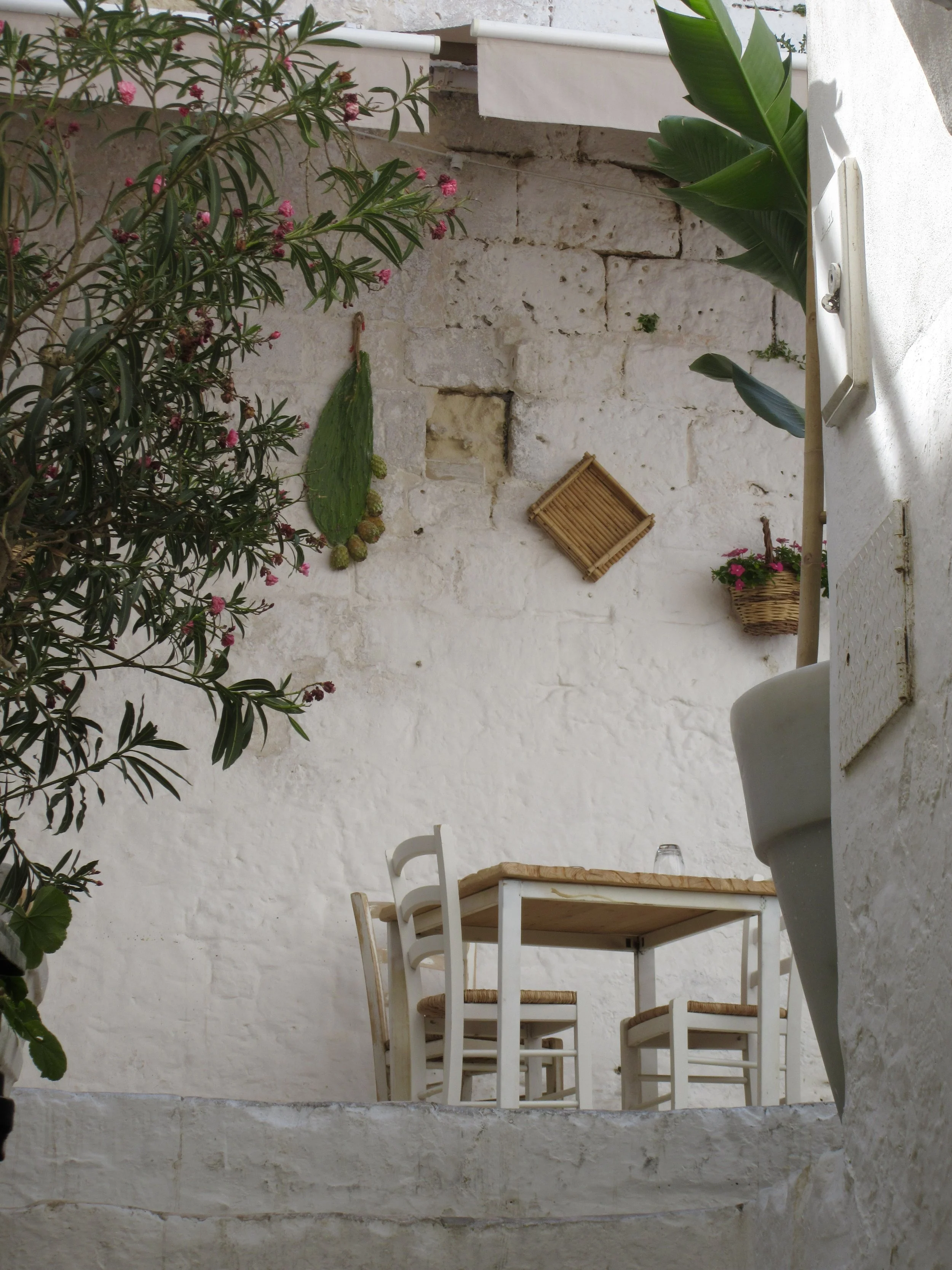 An empty table and chairs in a white-washed alley in Ostuni, Puglia.