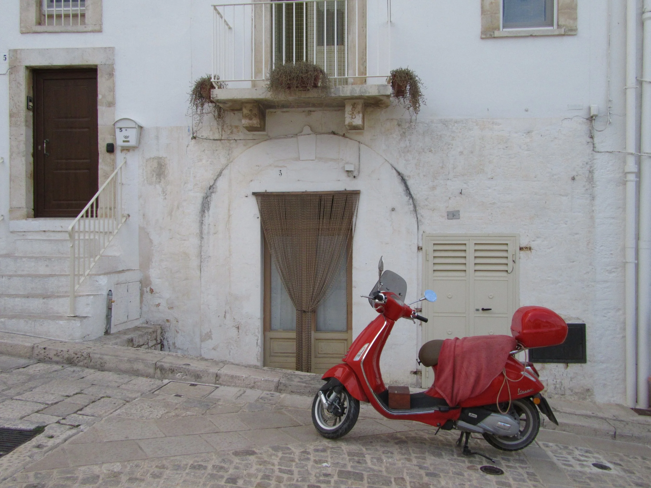 A red Vespa in front of a white-washed building in Alberobello, Puglia.