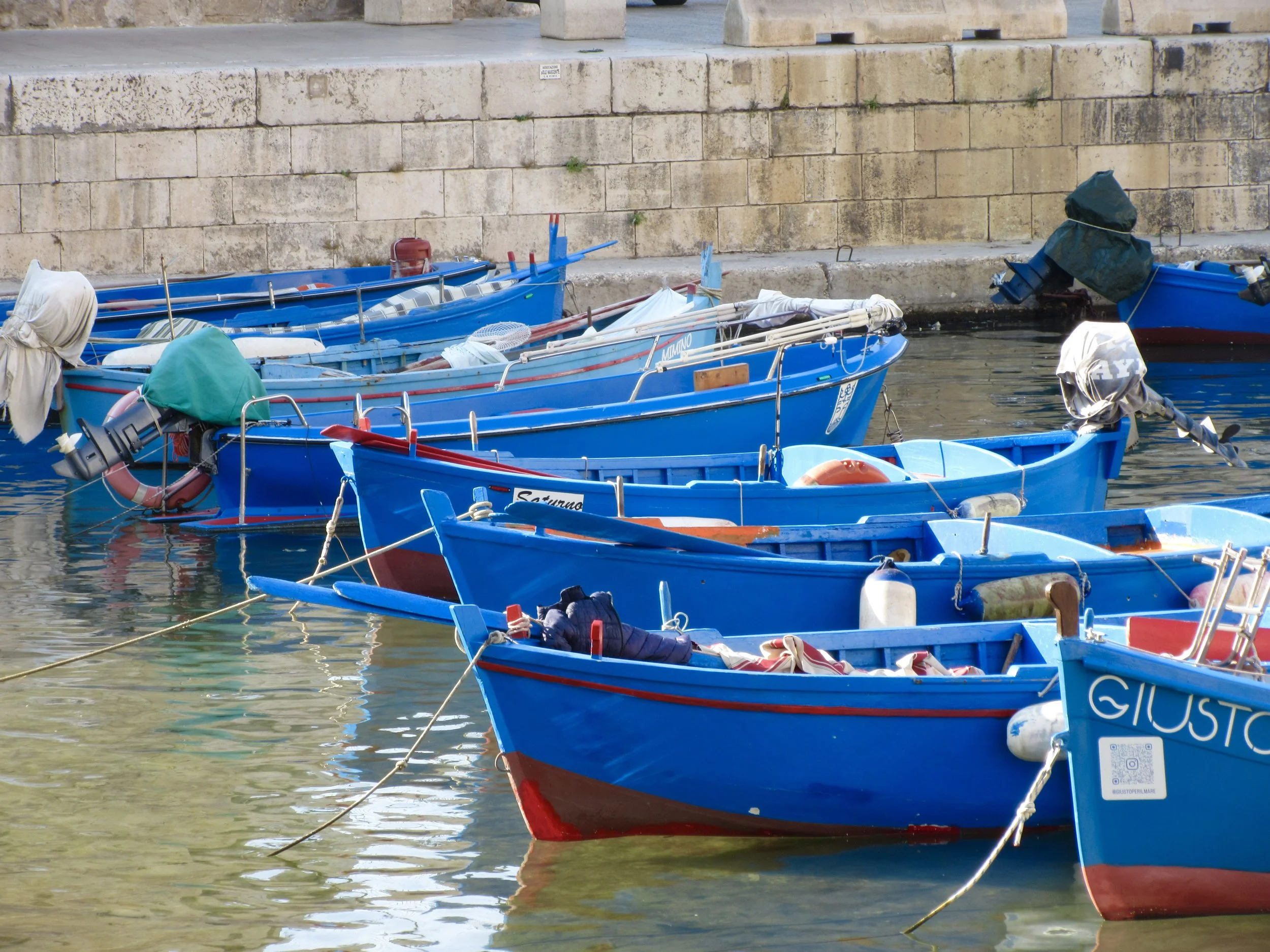 Blue and red fishing boats at the port in Monopoli, Puglia.