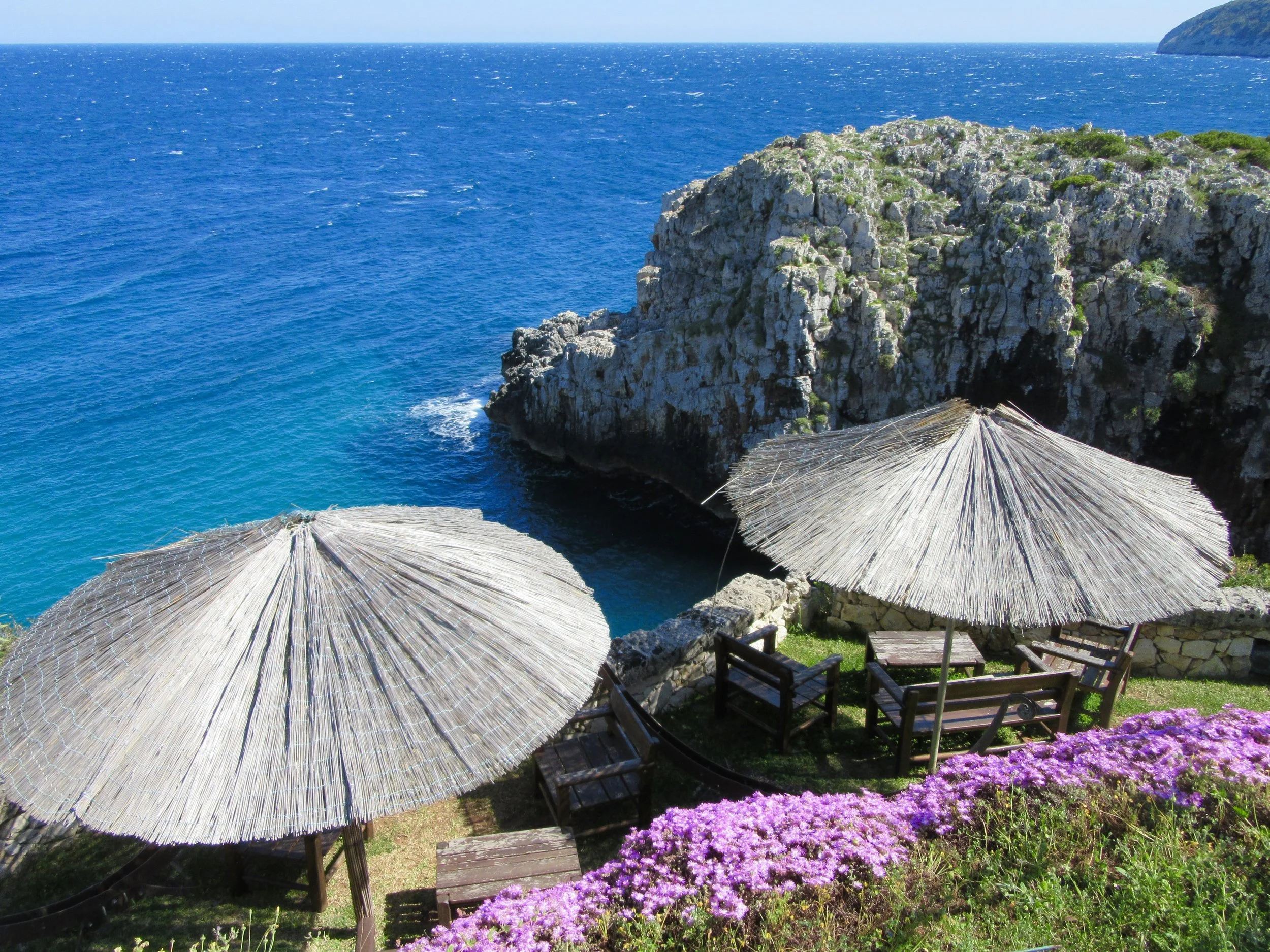 A view of the rocky cliffs and seating with umbrellas from Bar Ristorante L'Incanto near Gagliano del Capo.