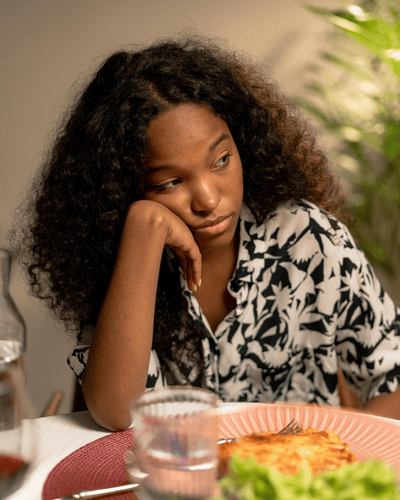 A teen experiencing a mood swing sitting at the dinner table