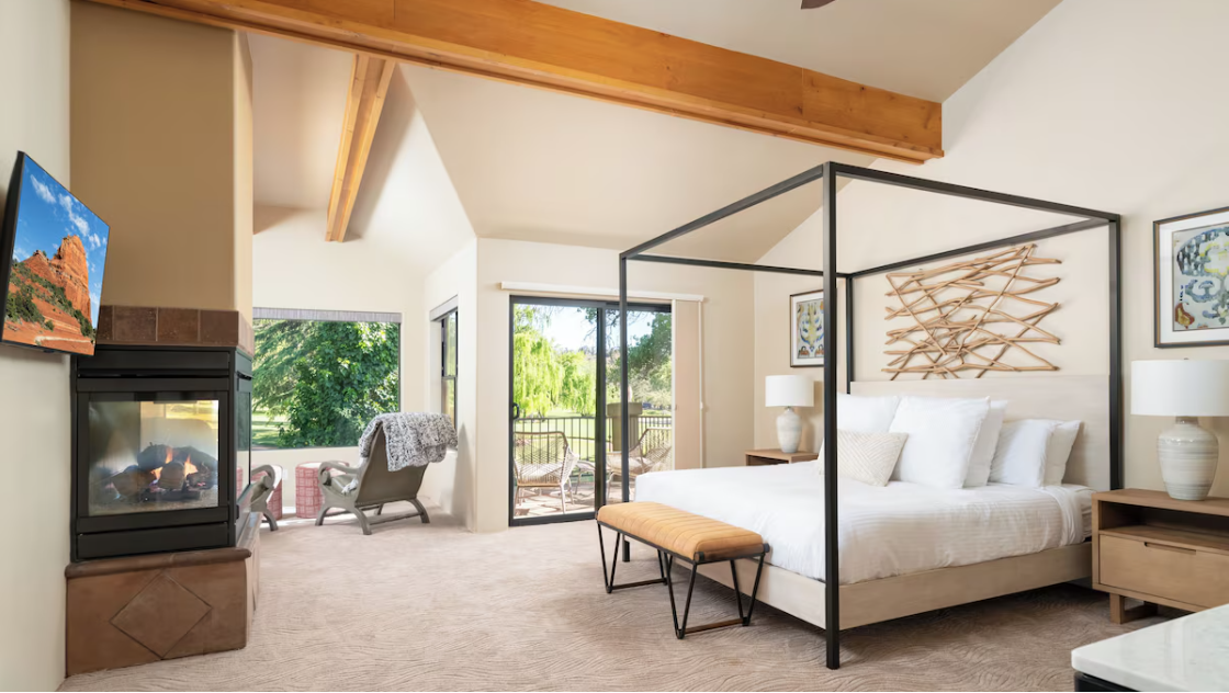 Modern bedroom with canopy bed, fireplace, and outdoor view.