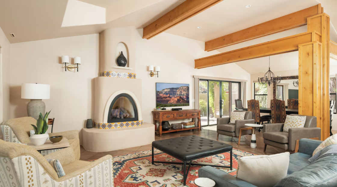 Spacious living room with kiva fireplace, wooden beams, modern furniture, and large windows.