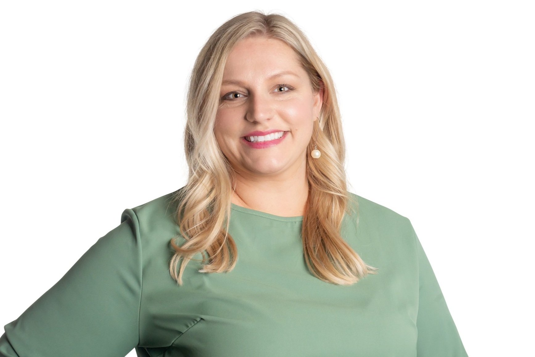 Woman with long blonde hair wearing a green top, smiling against a white background.
