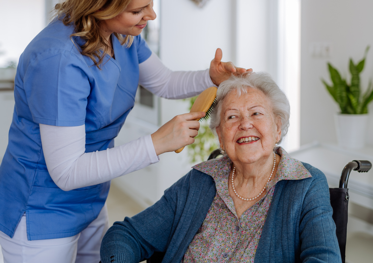A caregiver helping an older woman with her hair at home