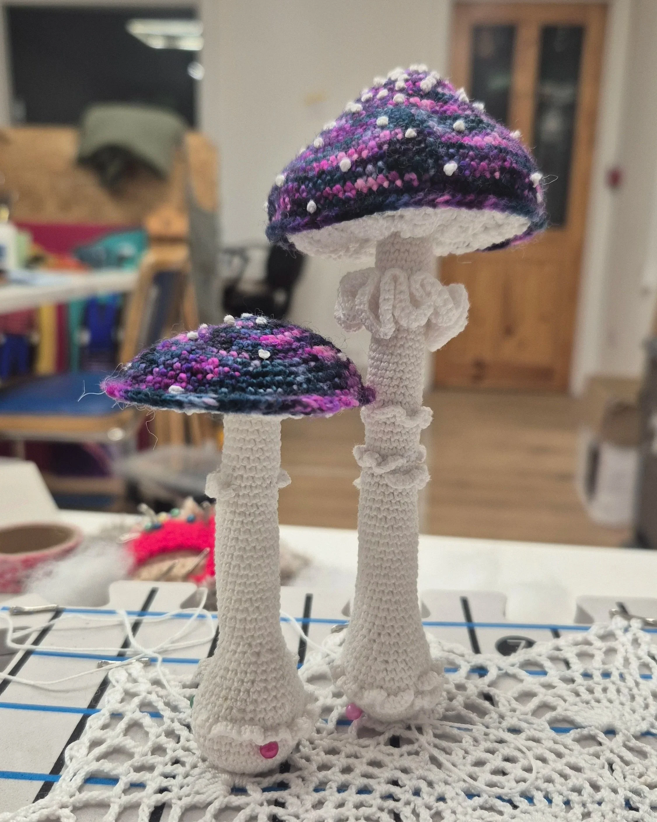 Two mushrooms - crocheted with crochet cotton thread, a 1mm hook, variegated yarn for the caps and embroidered french knots - based on the Amanita Virosa species of mushroom but with a coloured cap