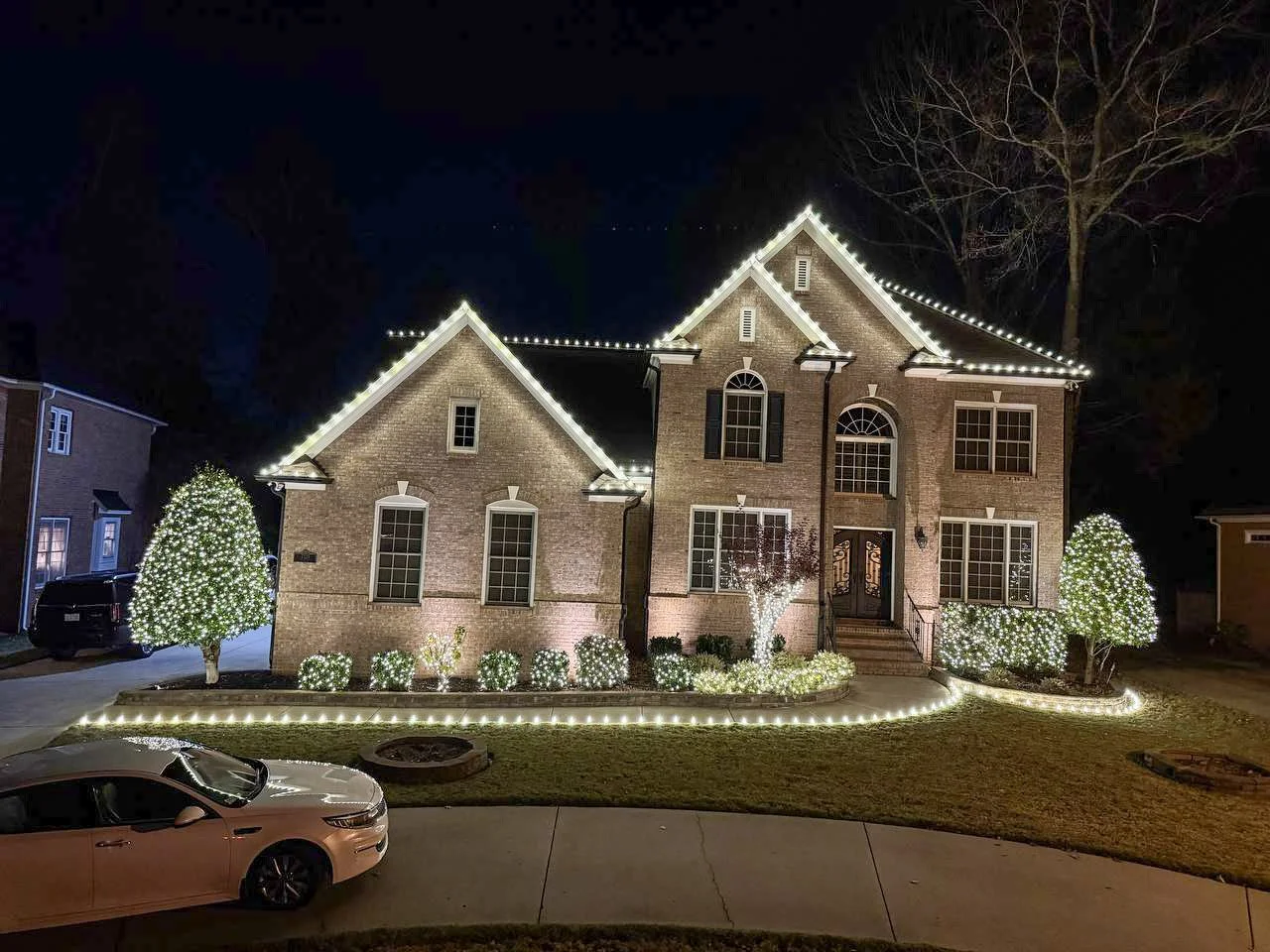 Large tree decorated with white Christmas lights by Vanguard Roofing Co., creating a bright, elegant outdoor holiday display in North Carolina.