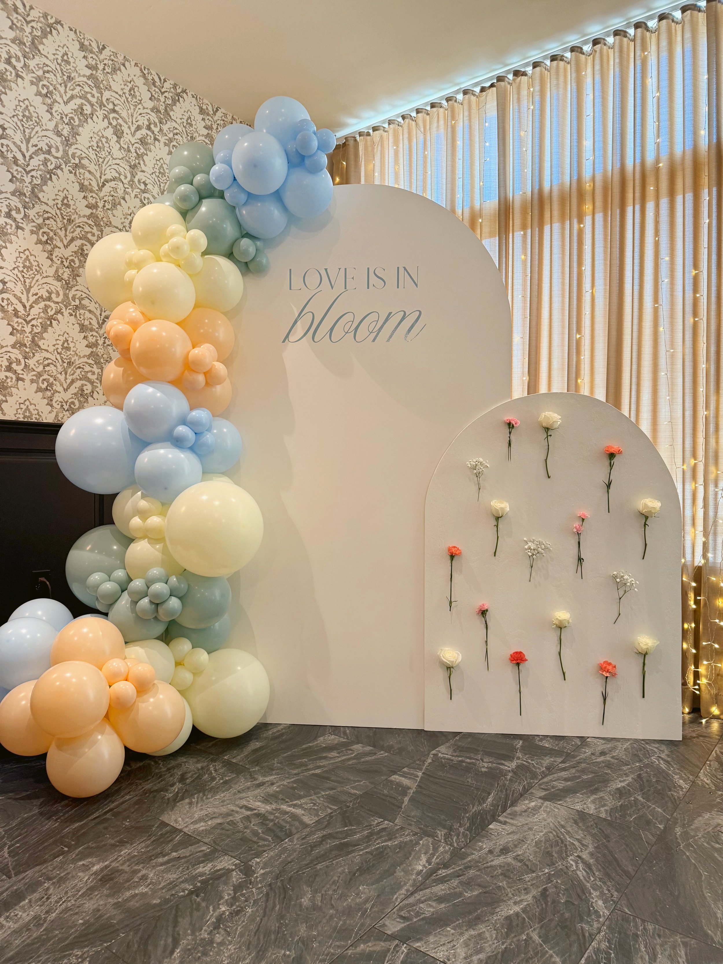 Love Is in Bloom bridal shower backdrop with 7-foot arch with custom vinyl, floral wall arch backdrop, and pastel organic balloon garland for bridal shower in Pennsylvania.