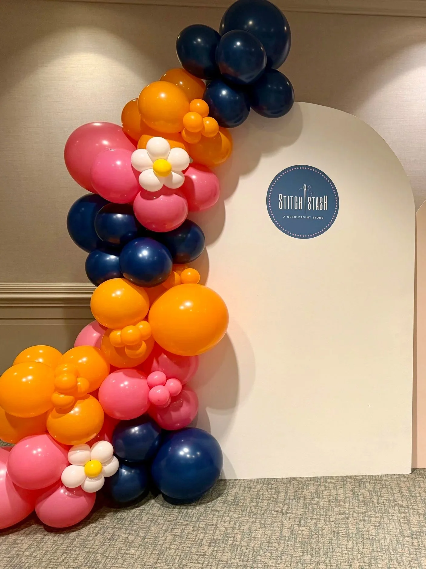 Colorful balloon arrangement for celebration next to a white display with a Stitch & Stash sign.