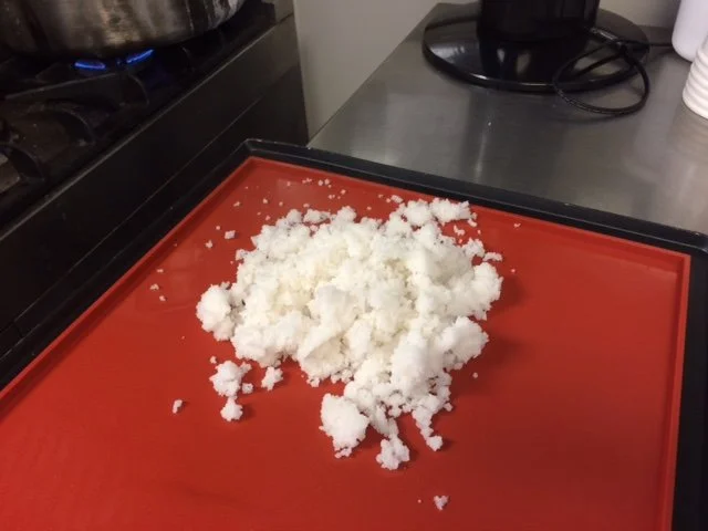 Sea salt sitting on a red tray on a stainless steel kitchen counter