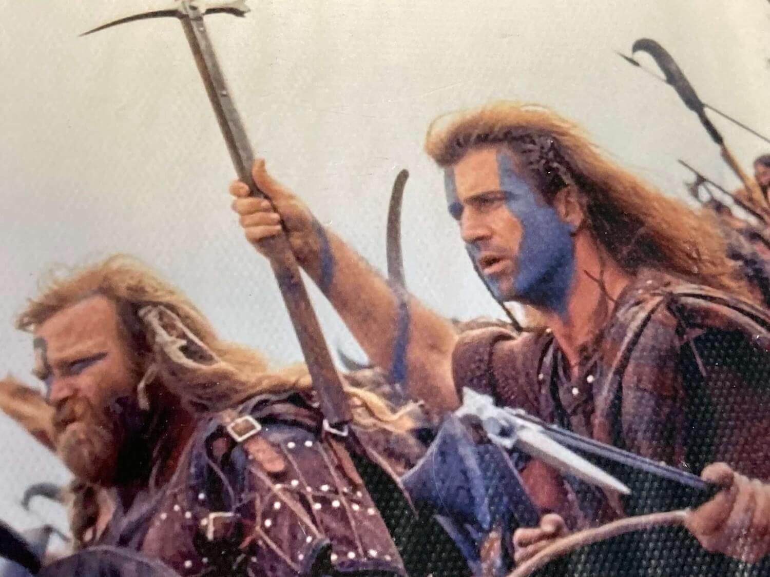 classic scene from movie Braveheart. Two men with long hair and blue face paint charging with weapons raised